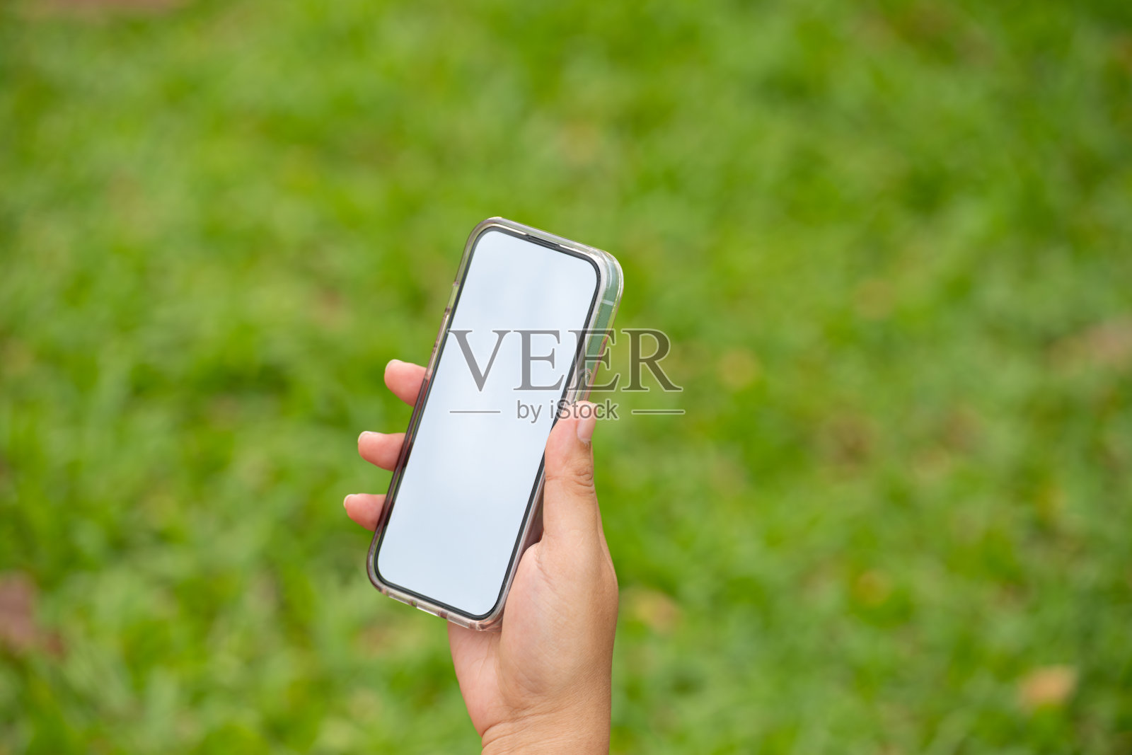 一名女子拿着白色屏幕的手机,手里拿着零食。他的屏幕显示了你的广告的空闲空间。技术和广告概念照片摄影图片