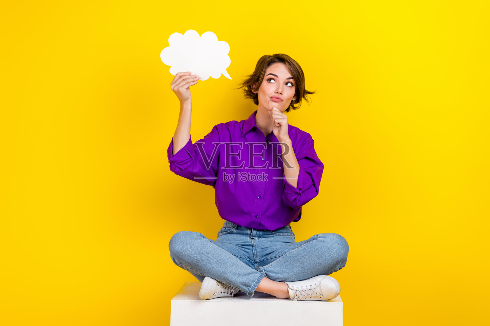 迷人的年轻女子抱着纸云穿着时髦的紫色智能休闲服孤立在黄色的背景照片摄影图片