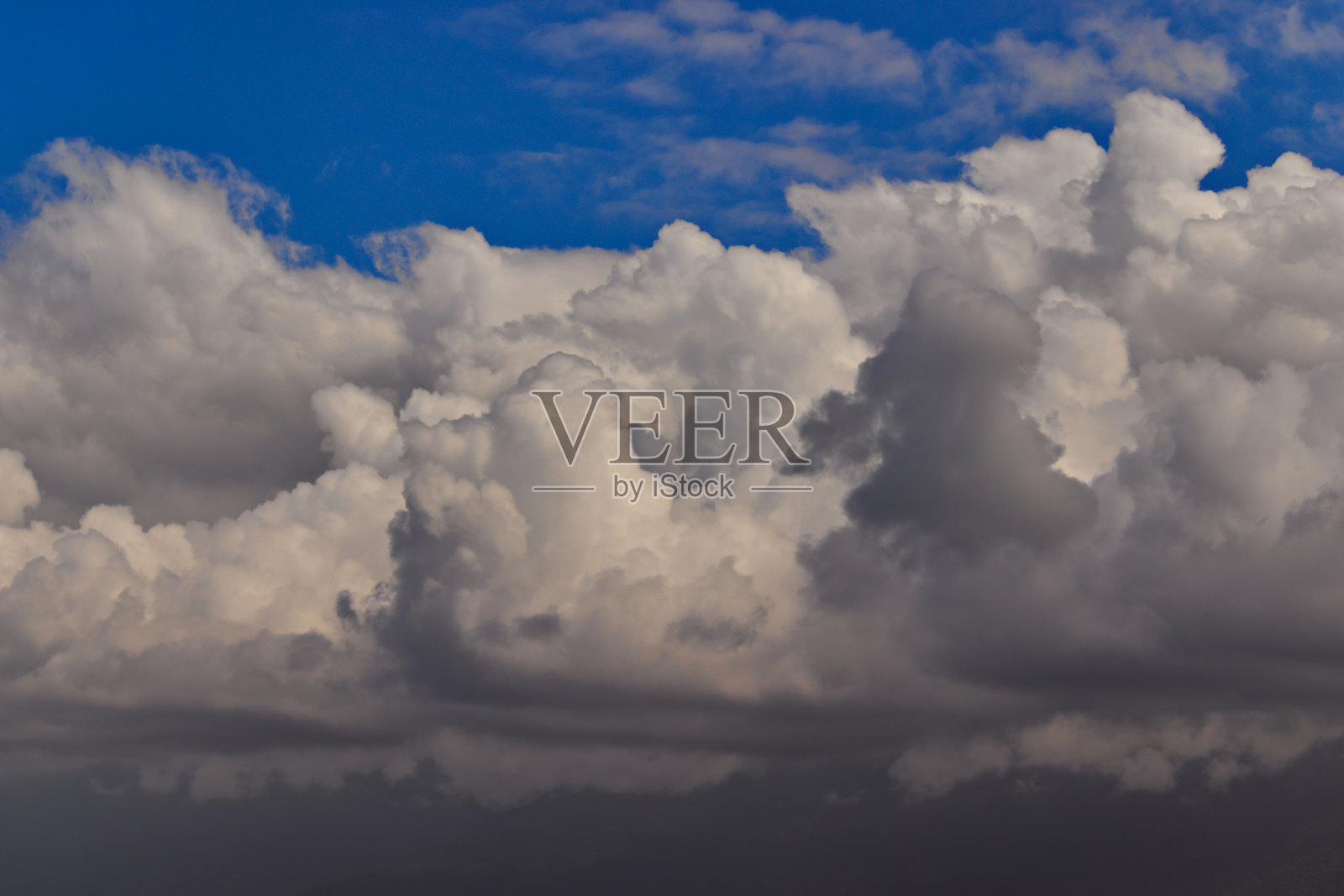 大片朦胧的积云,平静地漂浮在天边的一片蓝天上。照片摄影图片