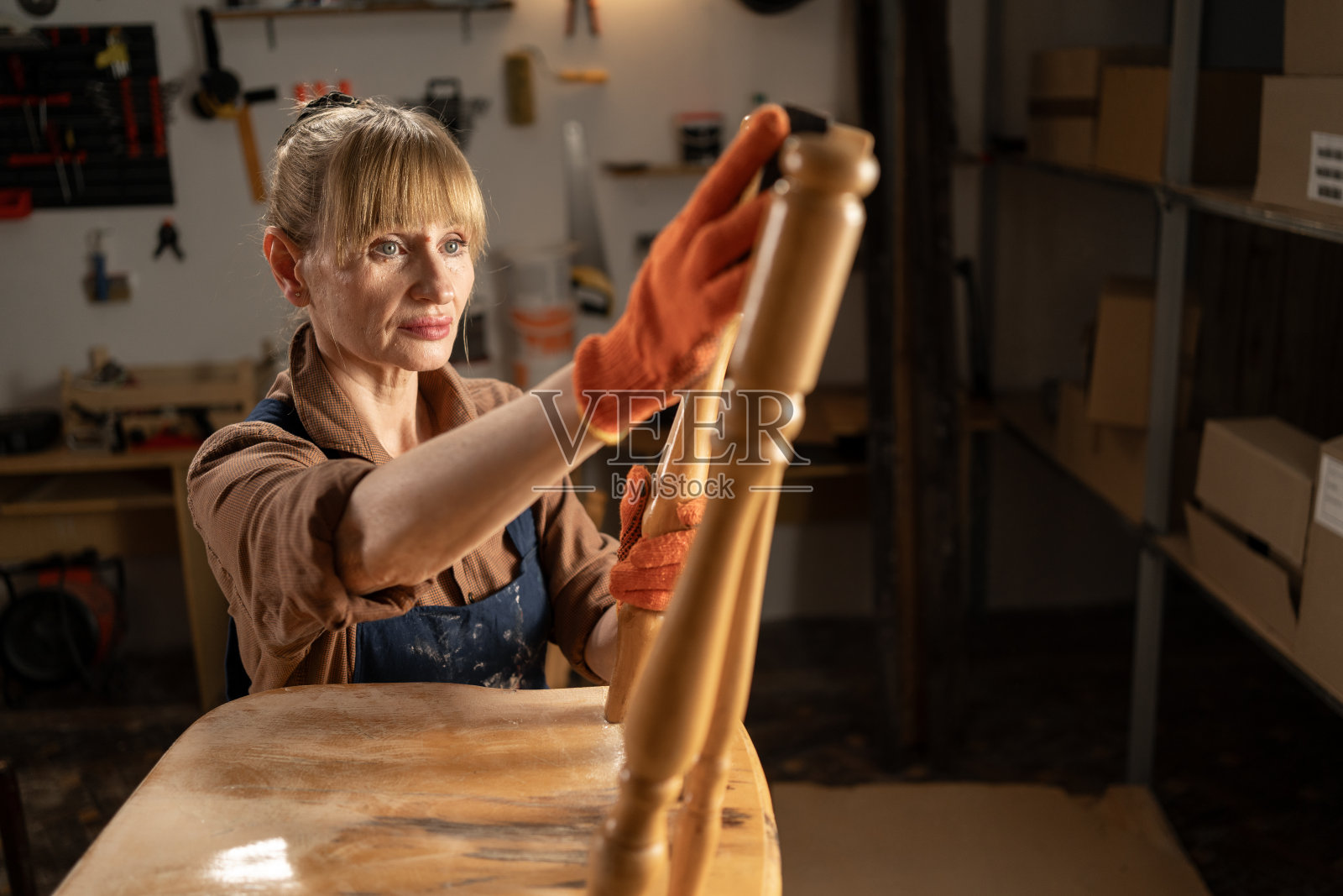 老妇人在车间修复旧木椅,特写照片摄影图片