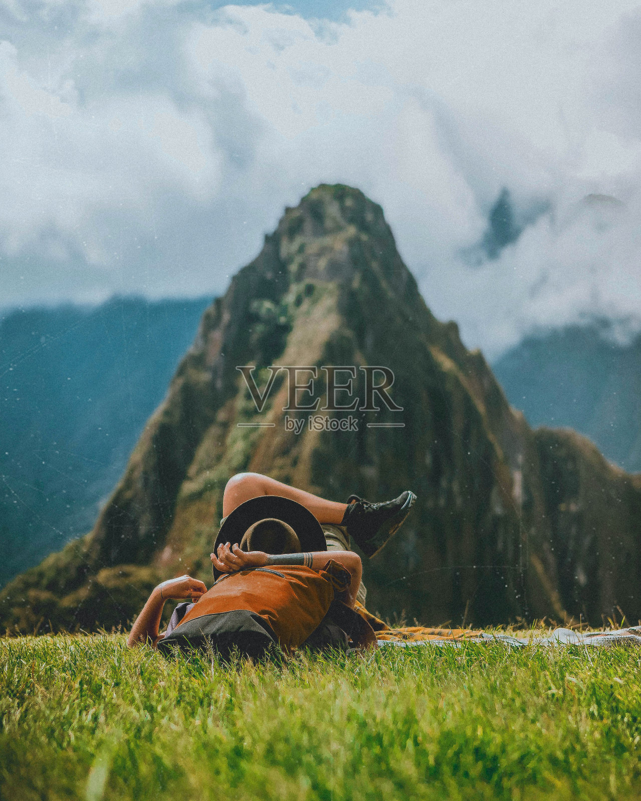 倚山躺在草地上的无忧无虑的女人照片摄影图片