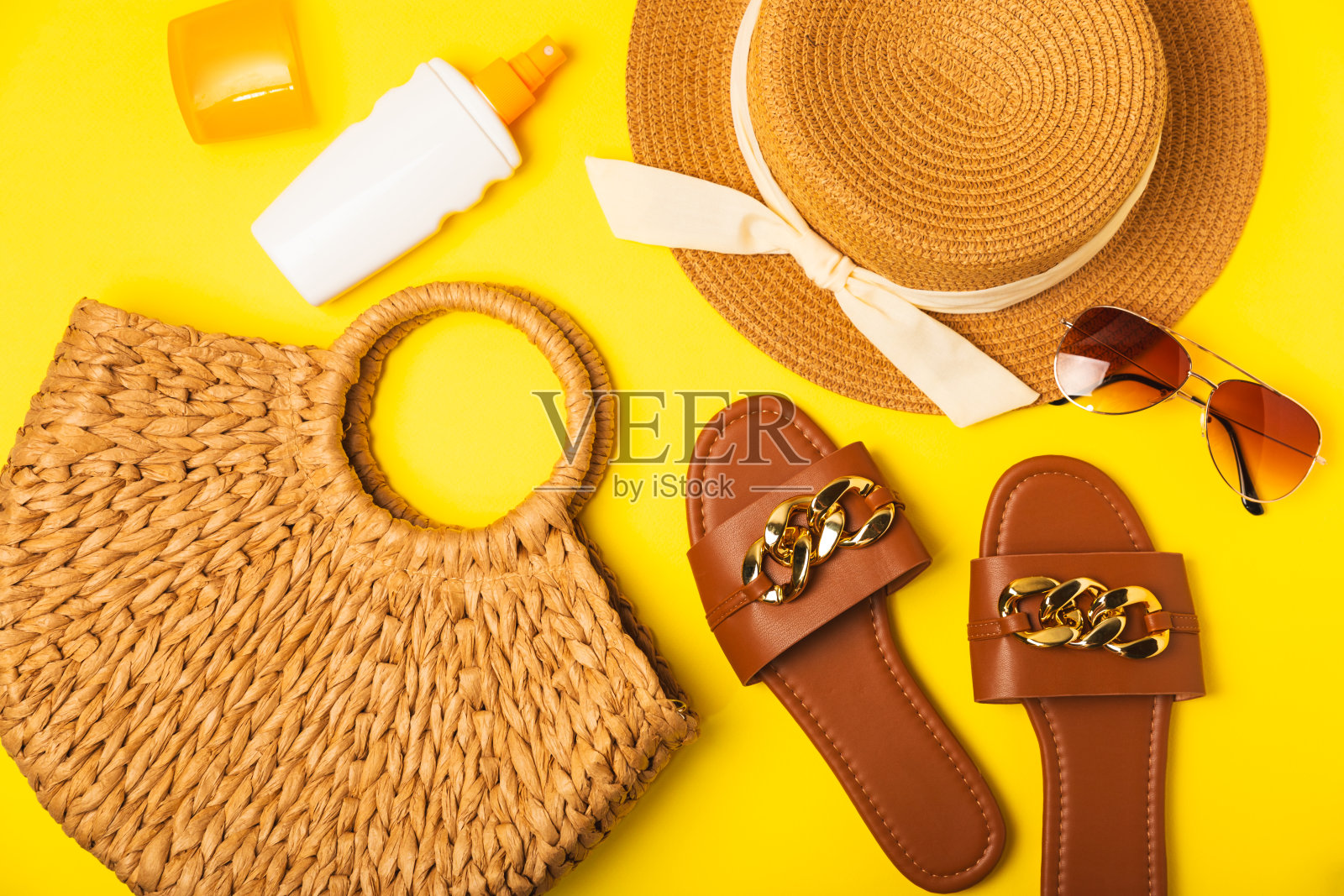 海滩配件。沙滩包里有帽子、沙滩巾、太阳镜、防晒霜和凉鞋,背景颜色鲜艳。热带度假概念。夏天的周末。平的。文本空间。本空间照片摄影图片