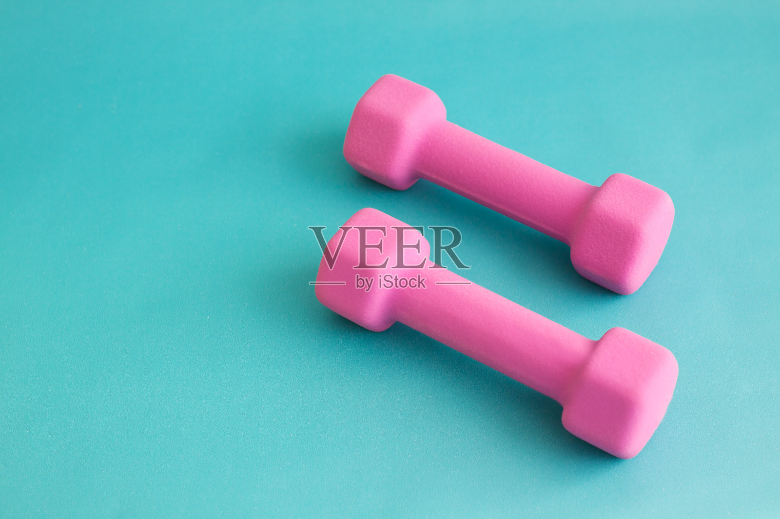 粉红色哑铃在绿松石背景的特写照片摄影图片