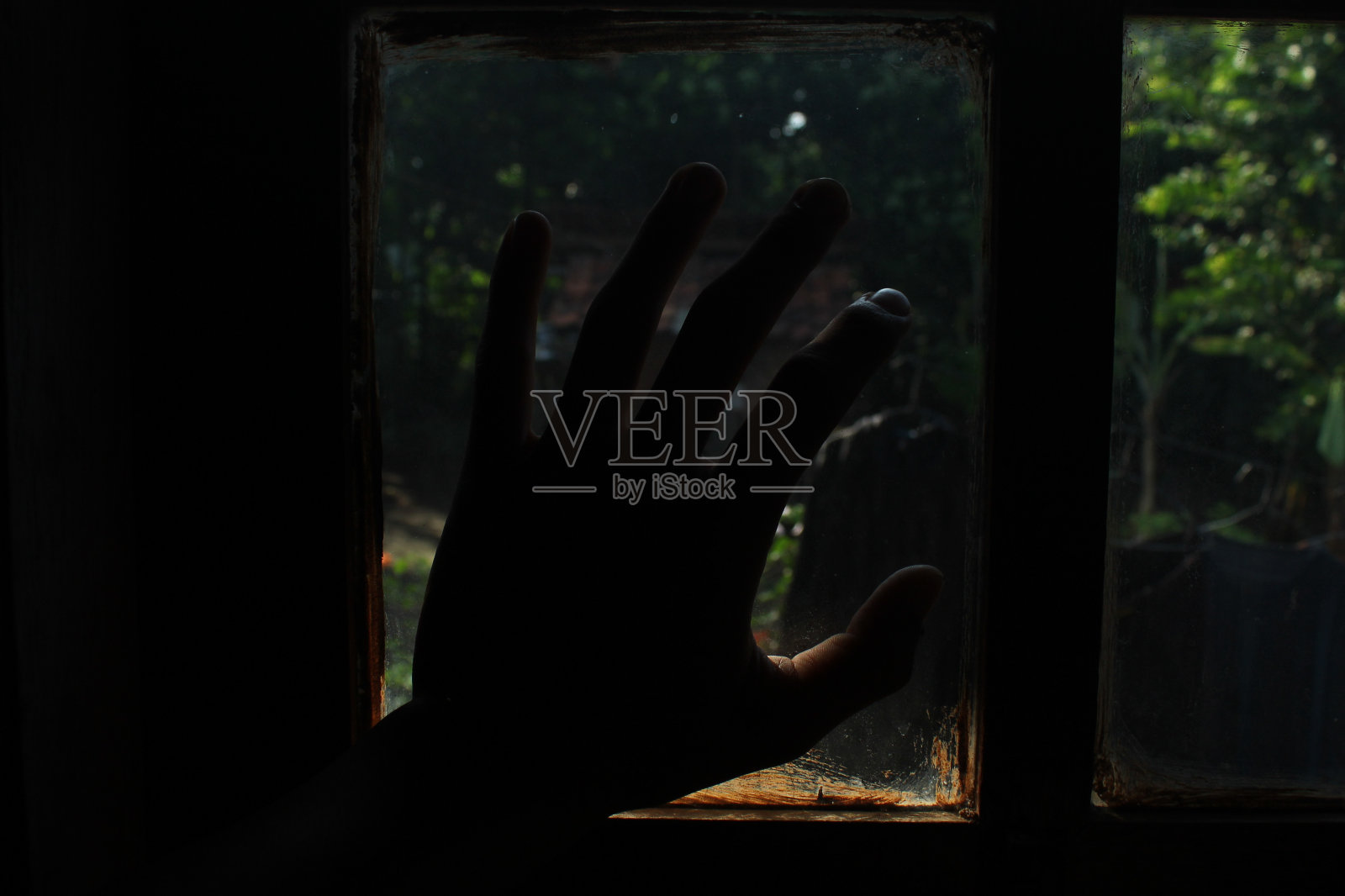 把手放在房子的玻璃窗上。有阳光的暗室照片摄影图片