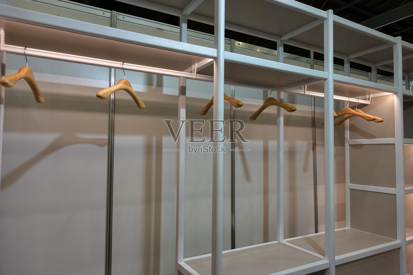 宽敞空旷的白色更衣室,有架子和木制衣架。衣橱的整体外观整洁有序。照片摄影图片