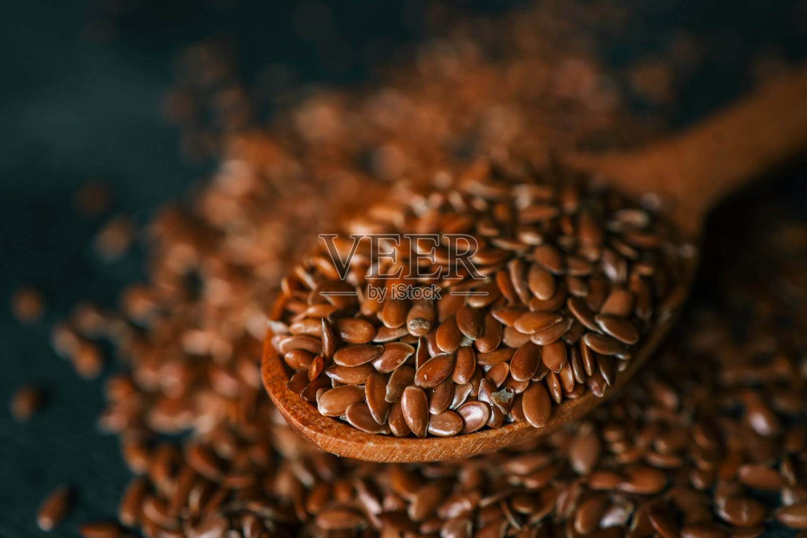 木勺与亚麻籽在黑色背景照片摄影图片