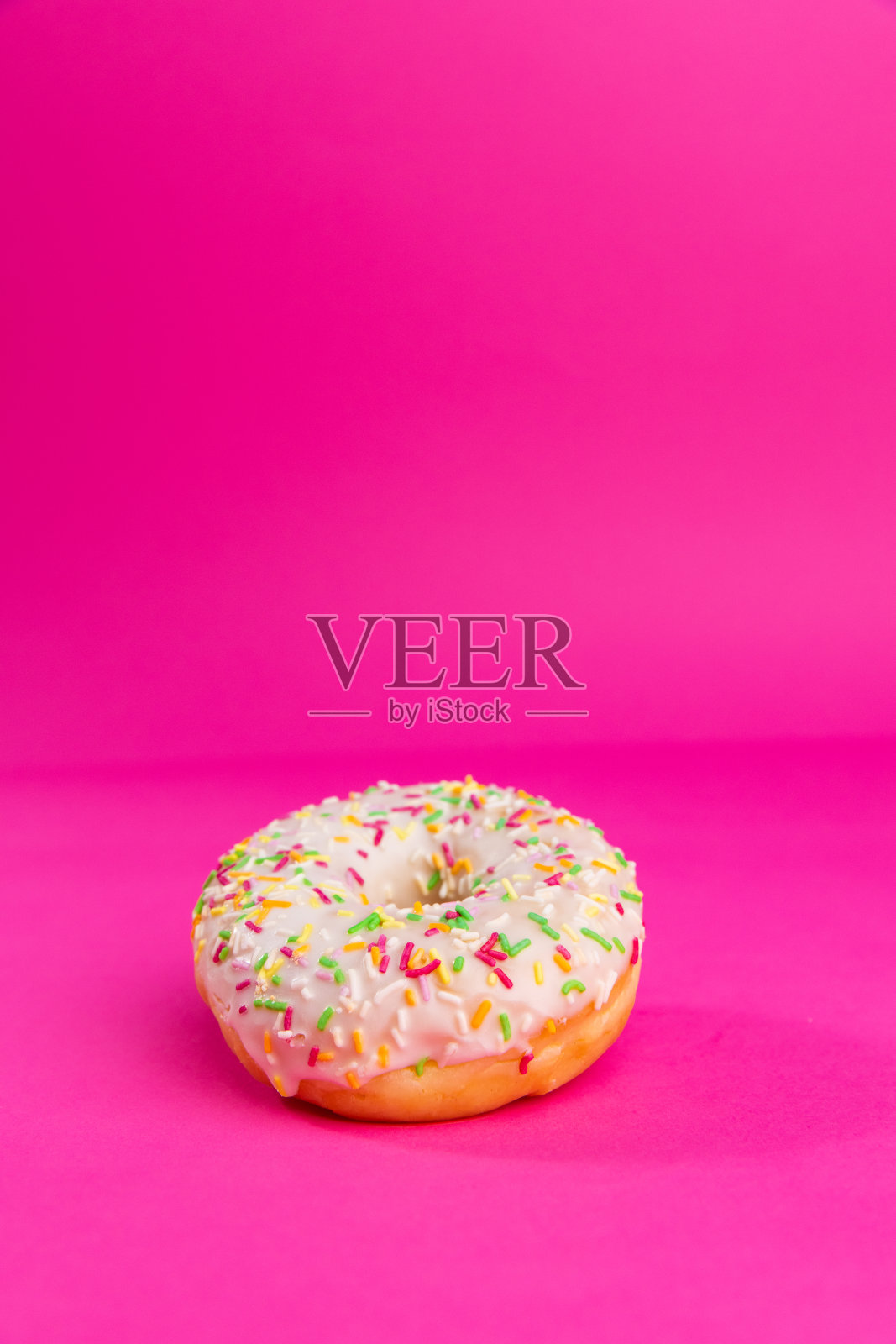 美味的甜甜圈与水果釉和装饰洒落在粉红色的背景-股票照片照片摄影图片