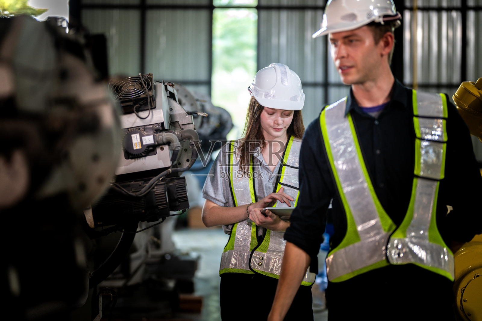 工厂工程师检查机器。自信团队成熟的商人用笔记本电脑站在工业机械臂旁,商人高空检测生产电子零件装置的技术。照片摄影图片