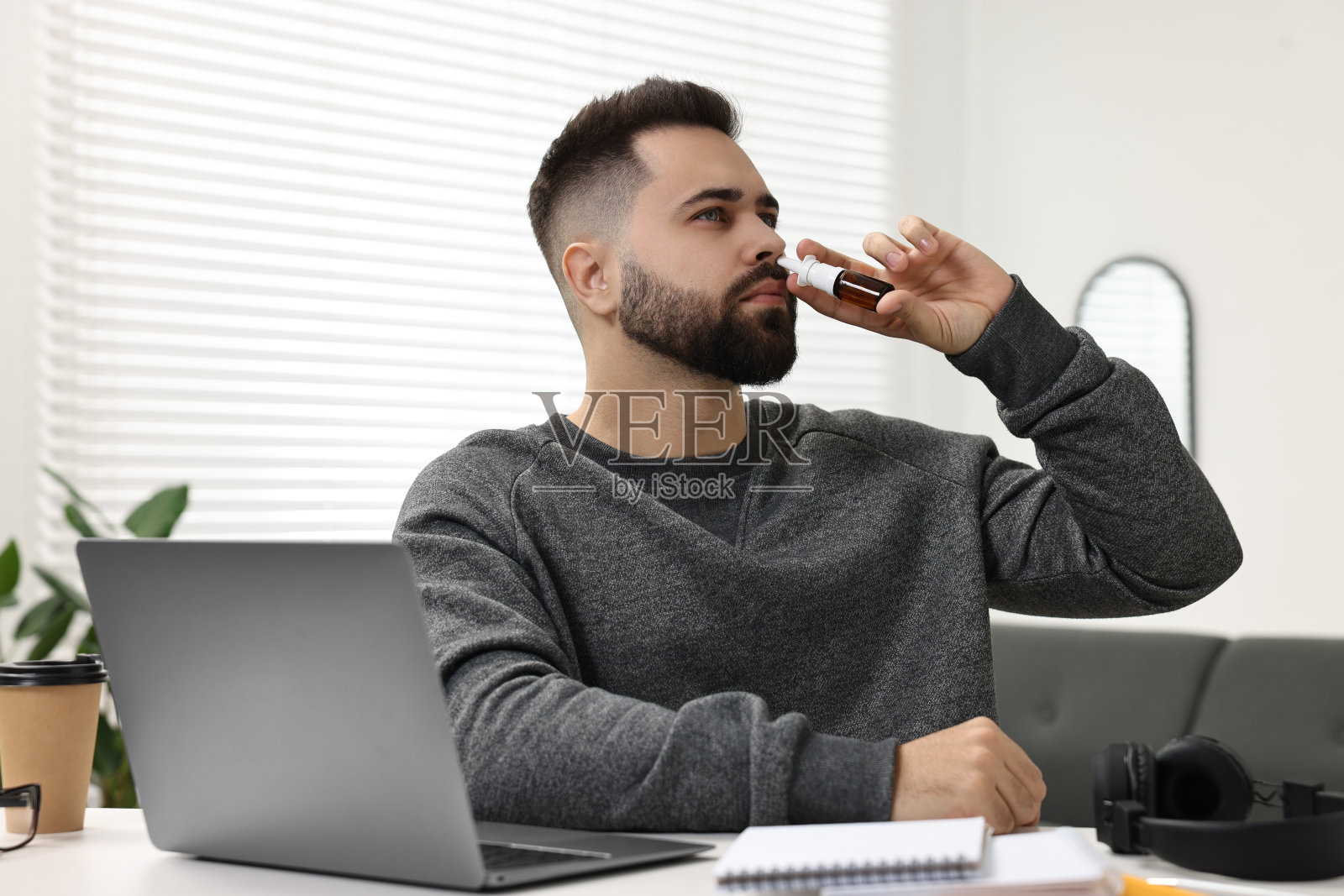 医疗滴。年轻人在室内餐桌上使用鼻腔喷雾剂照片摄影图片