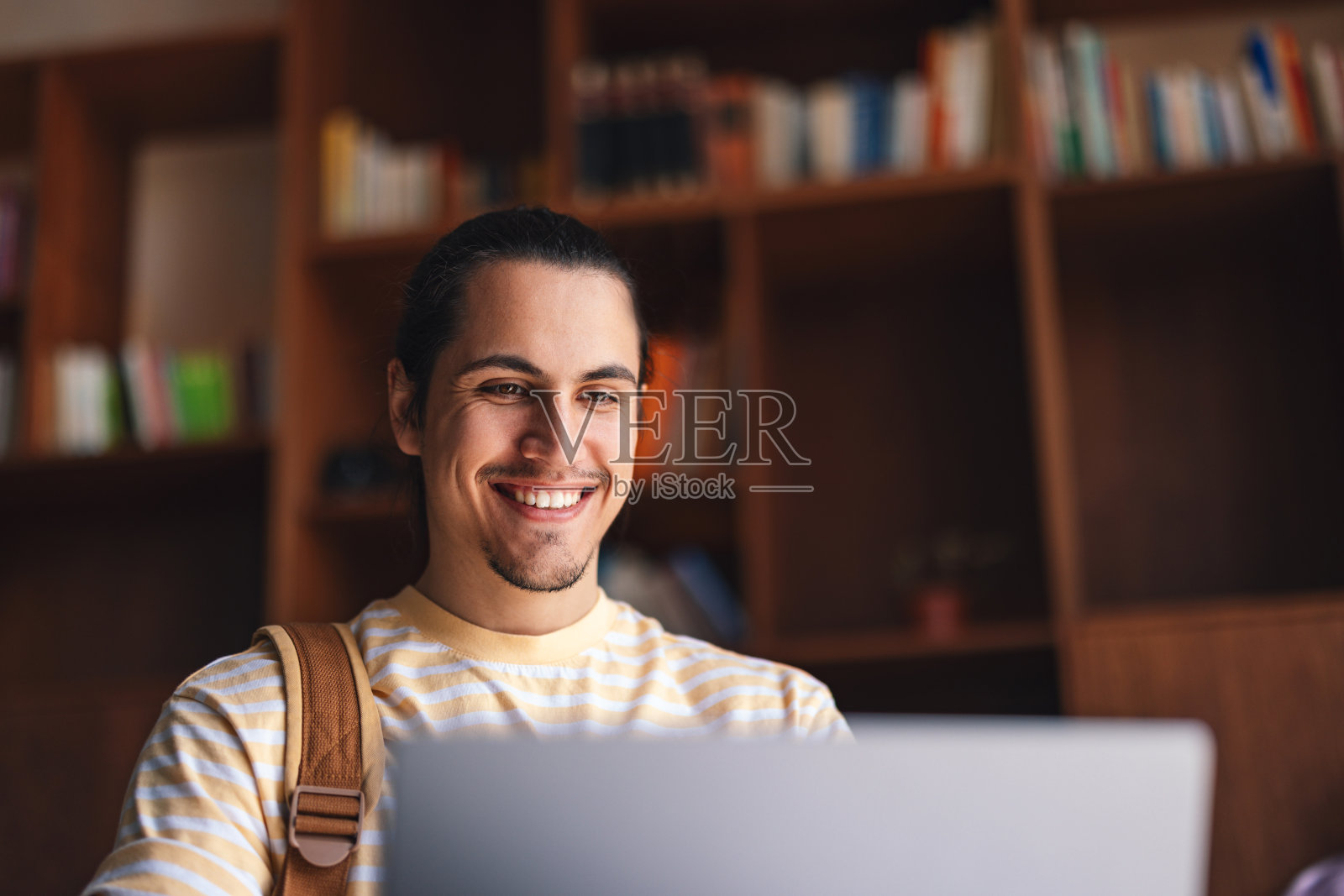 微笑的学生在图书馆用笔记本电脑学习照片摄影图片