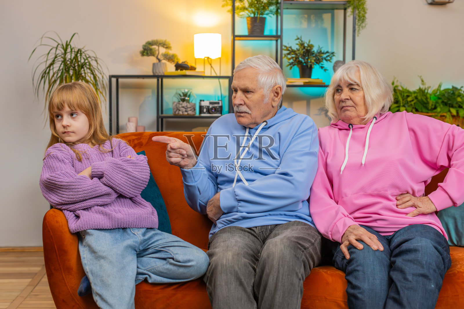 恼怒的祖父和祖母斥责孙女在家里沙发上的坏行为照片摄影图片