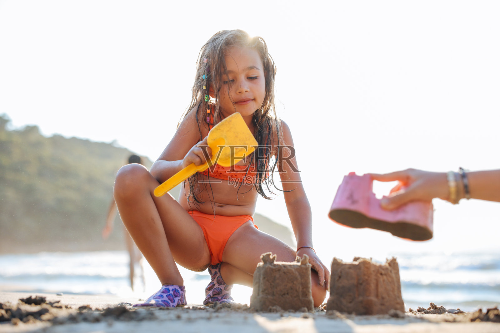 快乐的小女孩在堆沙堡。照片摄影图片