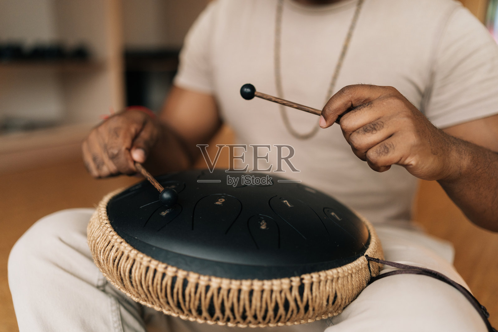 一个不知名的非洲人,用棍子在地板上以莲花的姿势坐着,弹奏着传统的民族音乐。照片摄影图片