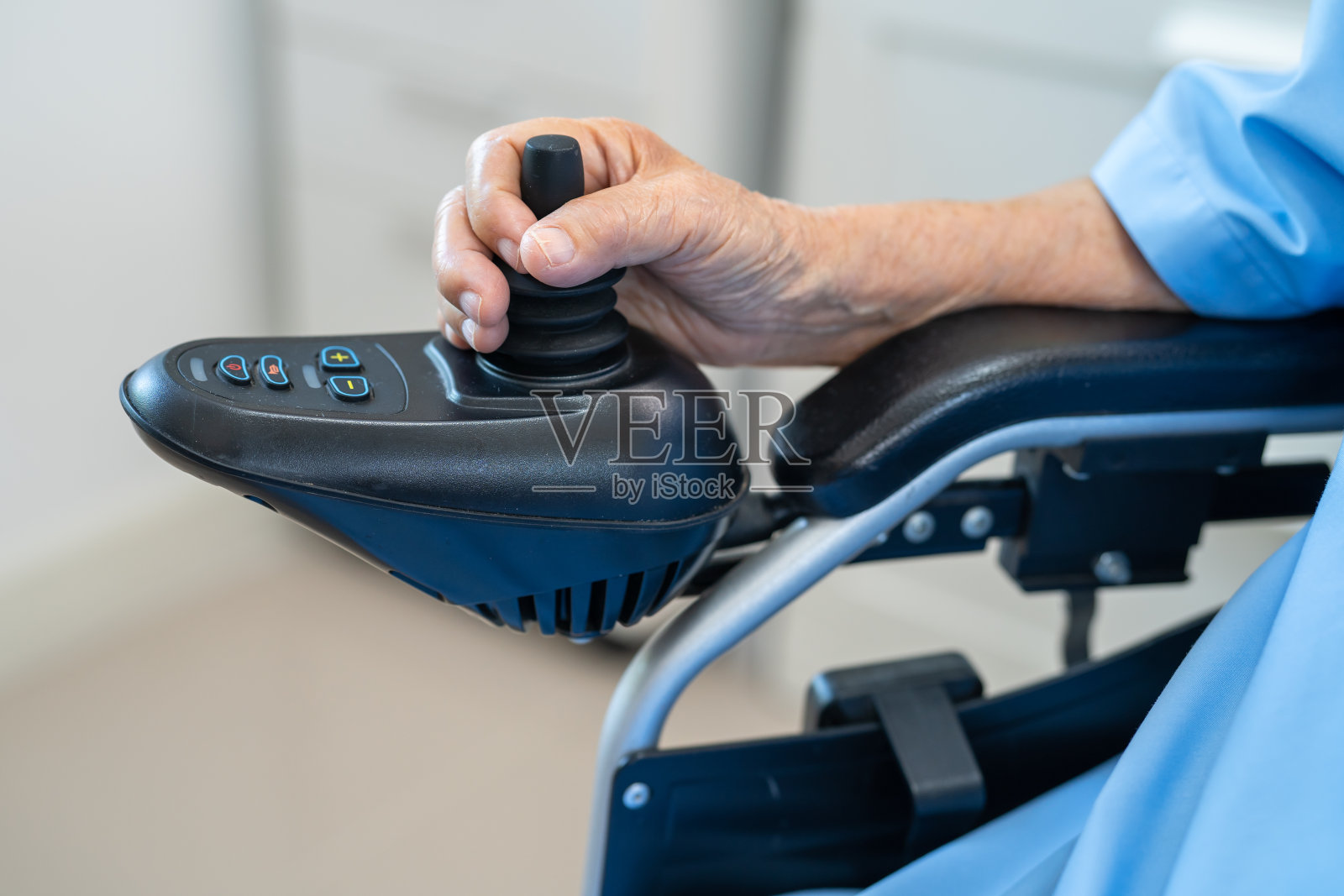 亚洲老年女性患者,在医院坐遥控电动轮椅,健康强壮。照片摄影图片