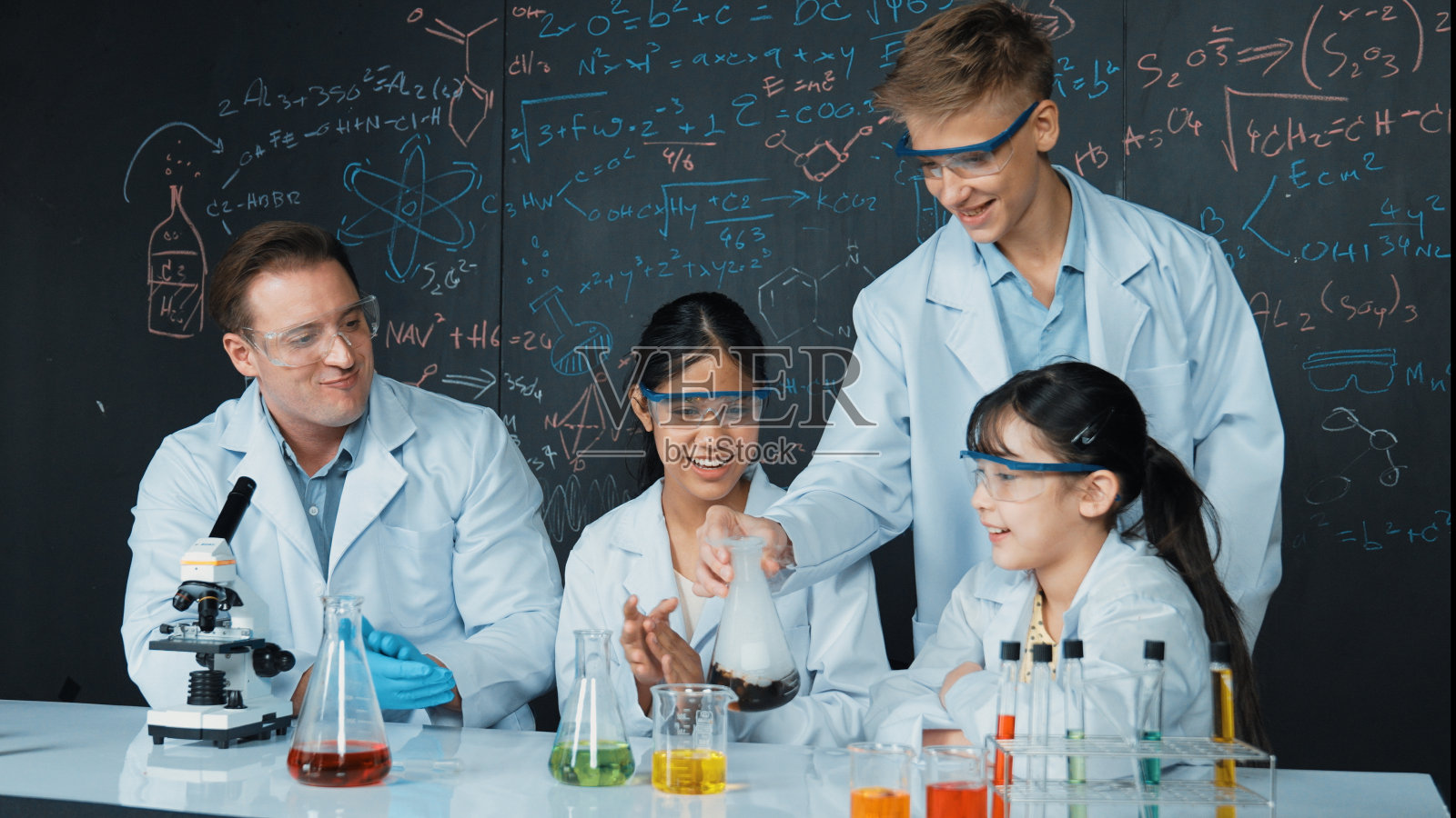 在STEM课上做实验时看着烧杯的可爱女孩。启迪。照片摄影图片