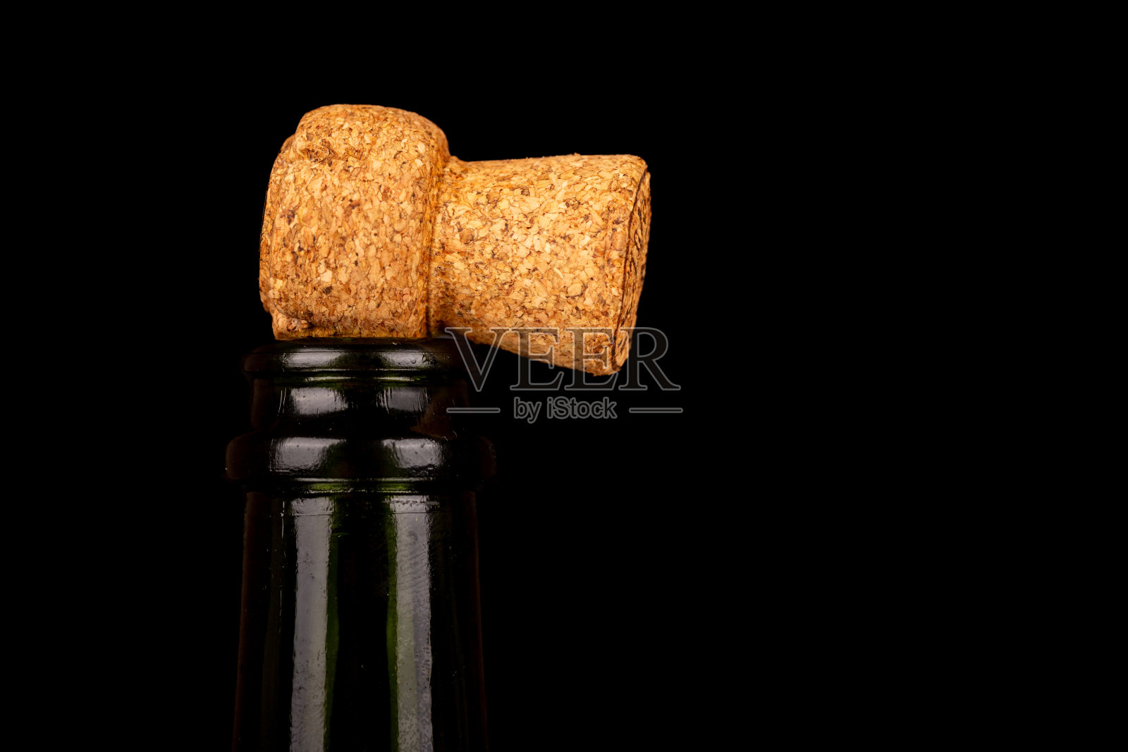 一个香槟软木塞放置在一个未开塞的瓶子顶部的特写,对黑色背景在左侧对齐。非常适合庆祝。照片摄影图片