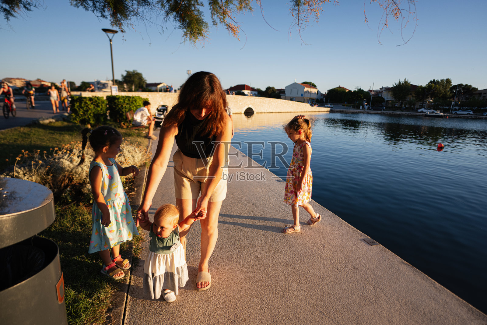 在克罗地亚尼恩的一个阳光明媚的日子里,母亲带着孩子在湖边散步。照片摄影图片