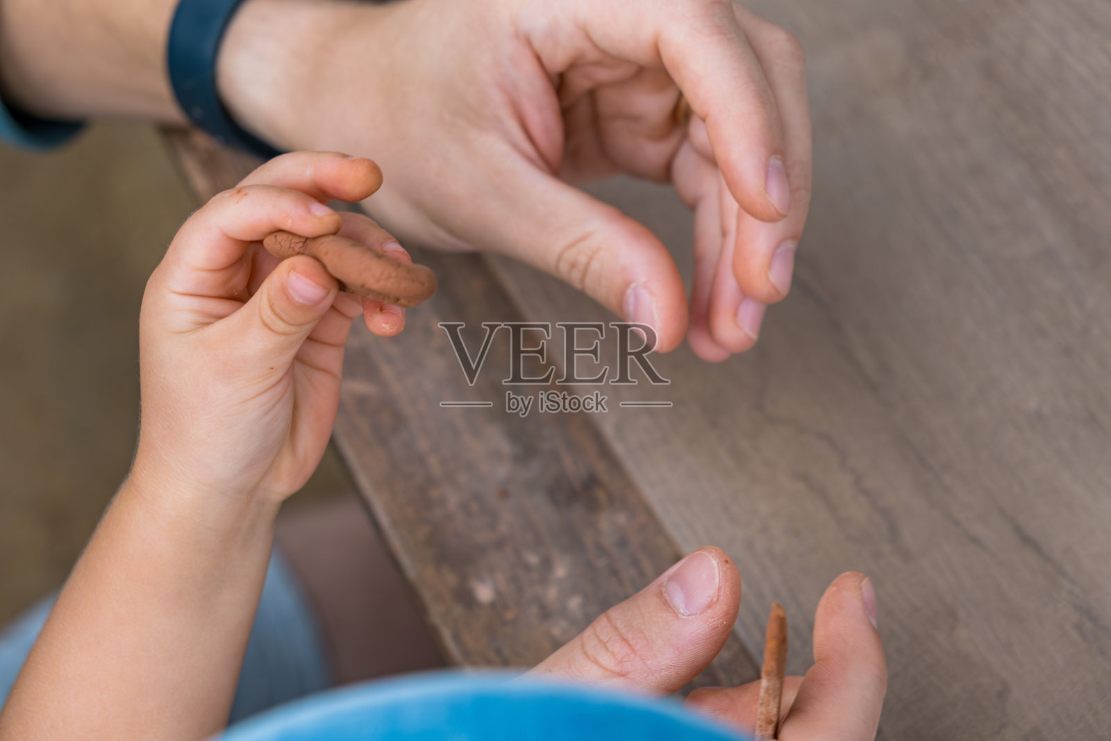 爸爸和小儿子在灰色的桌子旁工作,用红色的粘土塑造人物照片摄影图片