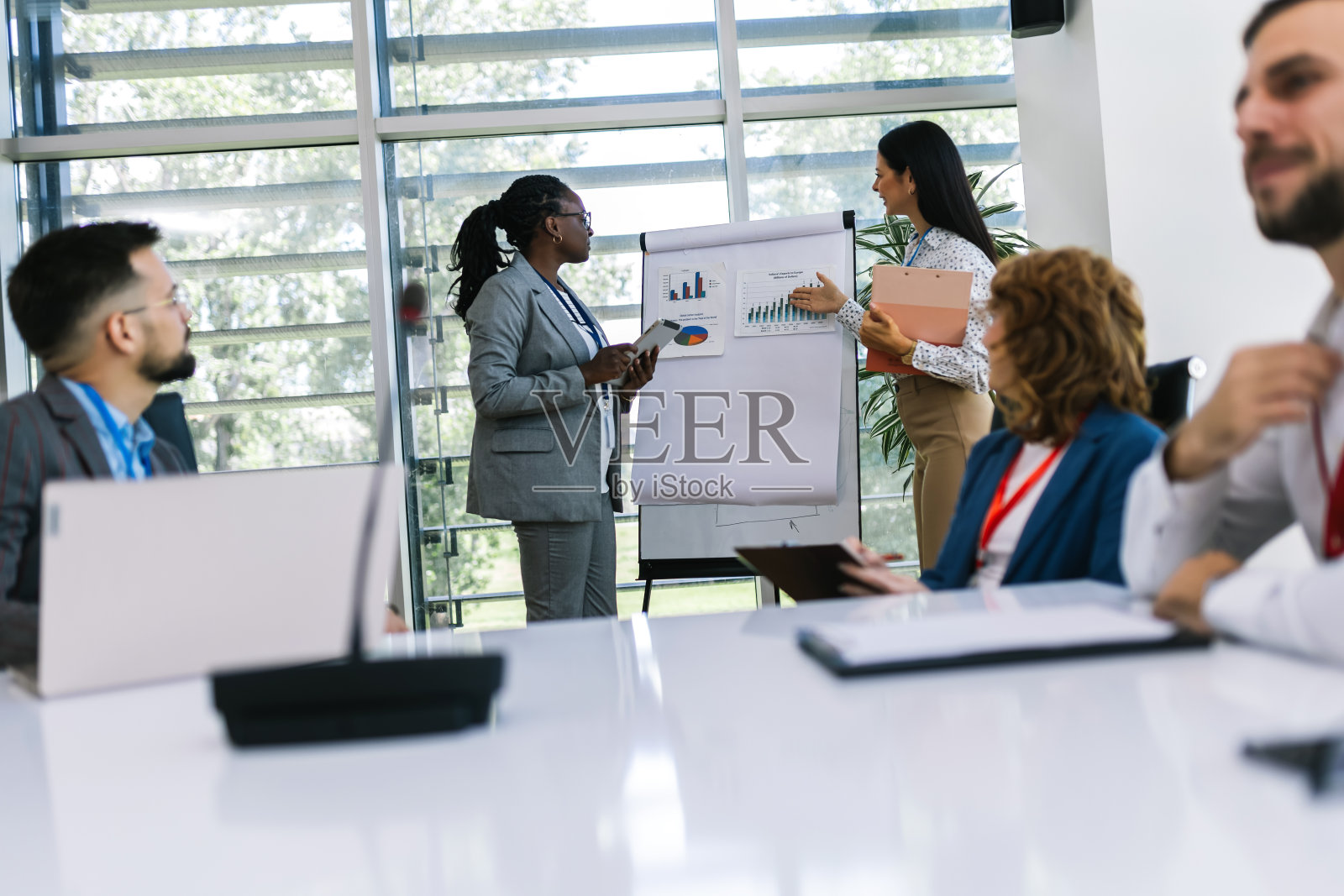 两个女商人在办公室里和其他同事开会。显示图形、图表和统计数据。照片摄影图片