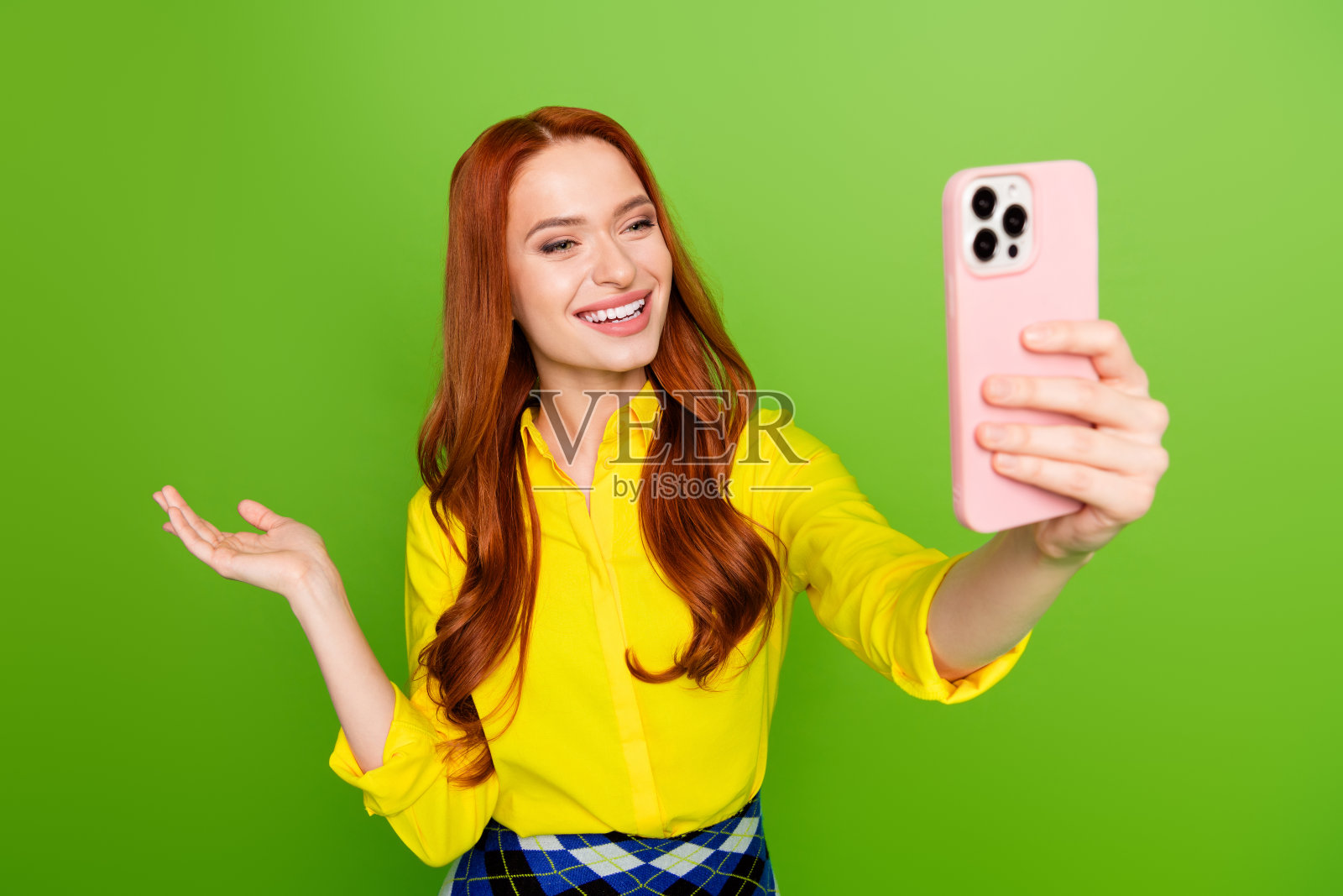 可爱可爱的女人穿着黄色时尚的衣服,在绿色的背景下拍摄视频自拍照片摄影图片