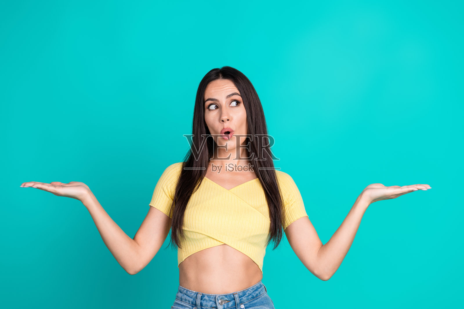 漂亮的年轻女子的肖像看起来持有空白的空间,并穿着顶部孤立的绿松石色背景照片摄影图片