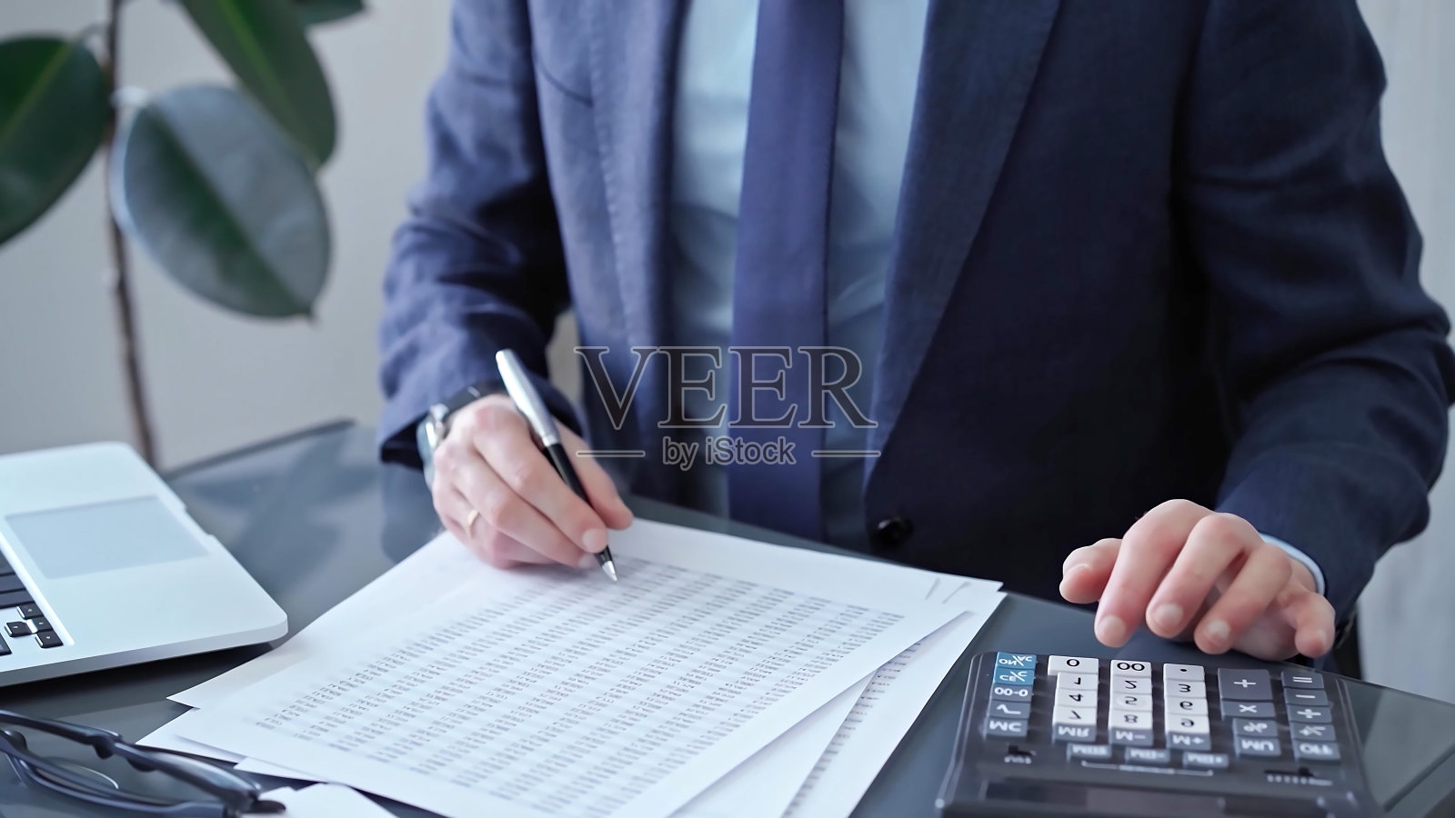 商人在笔记本电脑和计算器上分析财务数据。专业审计员处理财务报告的特写。经营理念照片摄影图片