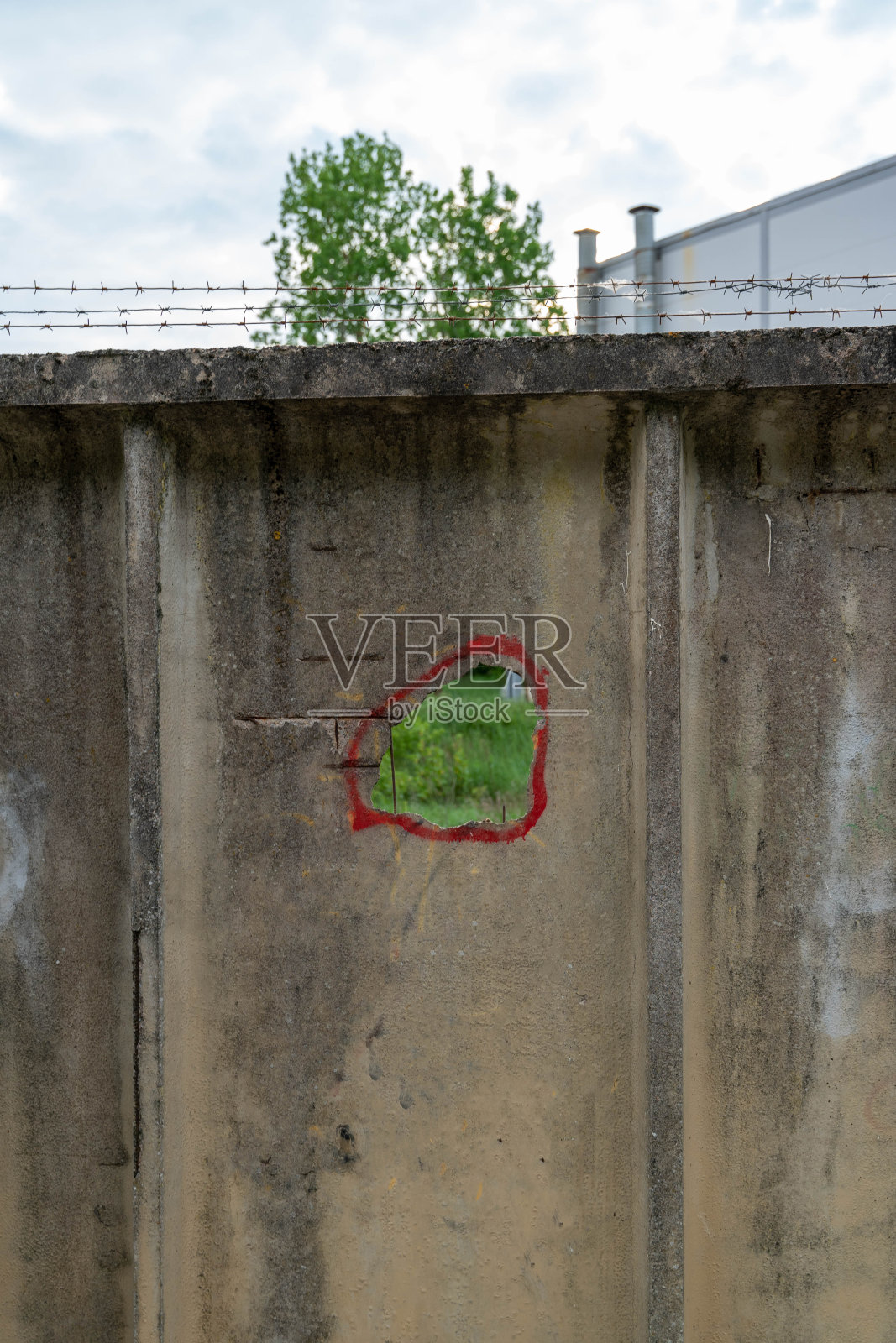 有铁丝网和洞的墙用红色圈起来照片摄影图片