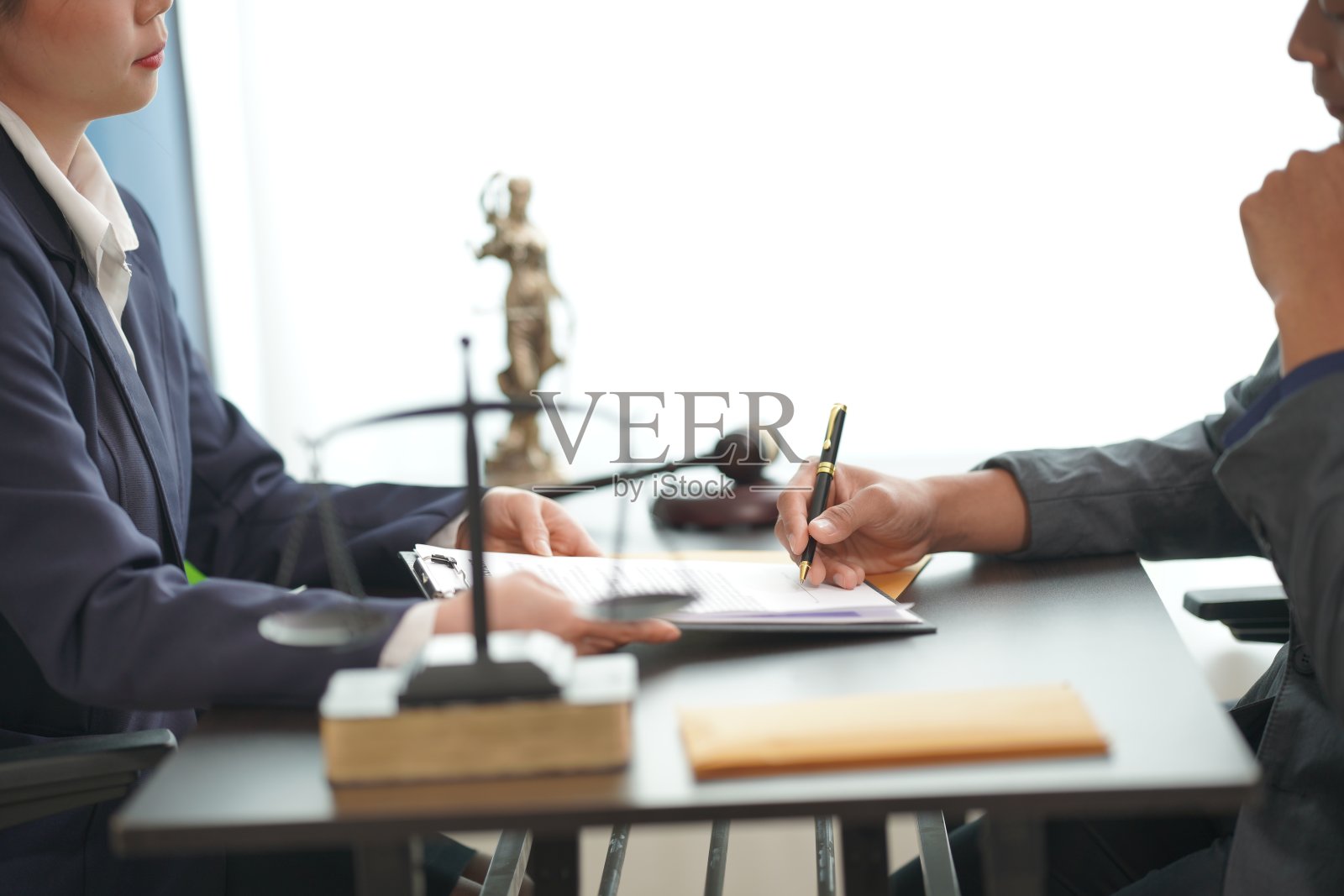 两名西装革履的商人正在用锤子检查文件。这可能是在讨论案件或在会议中进行调解时,正在用锤子检查法律文件。正义的尺度照片摄影图片