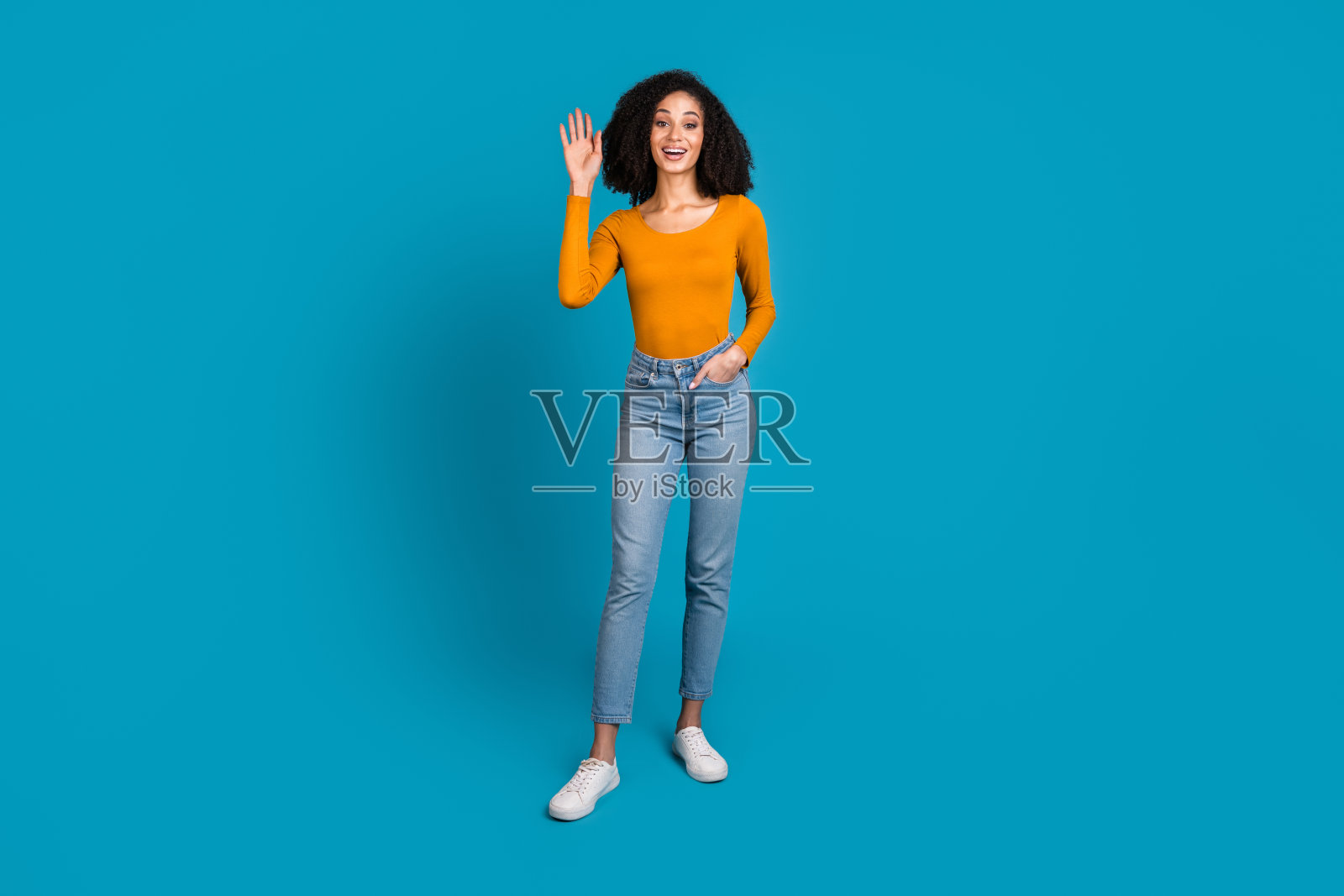 迷人的年轻女子的全身照片挥手hi穿着时尚的黄色衣服孤立的蓝色背景照片摄影图片