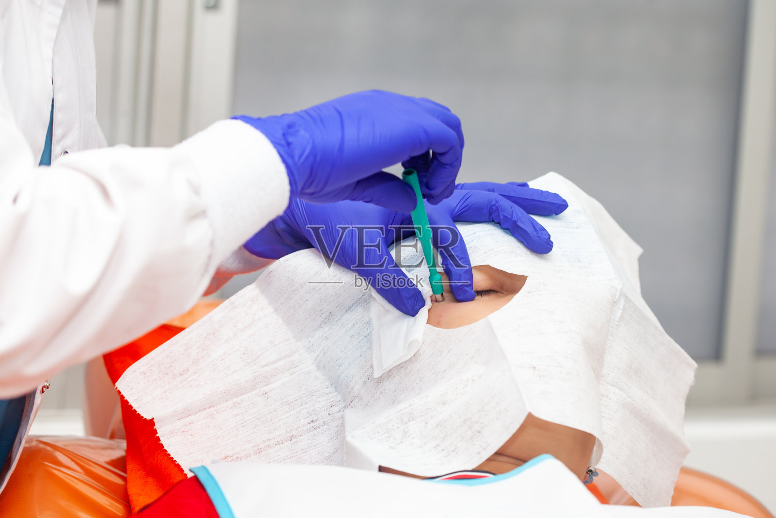 皮肤病变去除程序。皮肤科医生正在为一位年轻男性病人的面部进行良性皮肤病变的切除。活检穿孔照片摄影图片