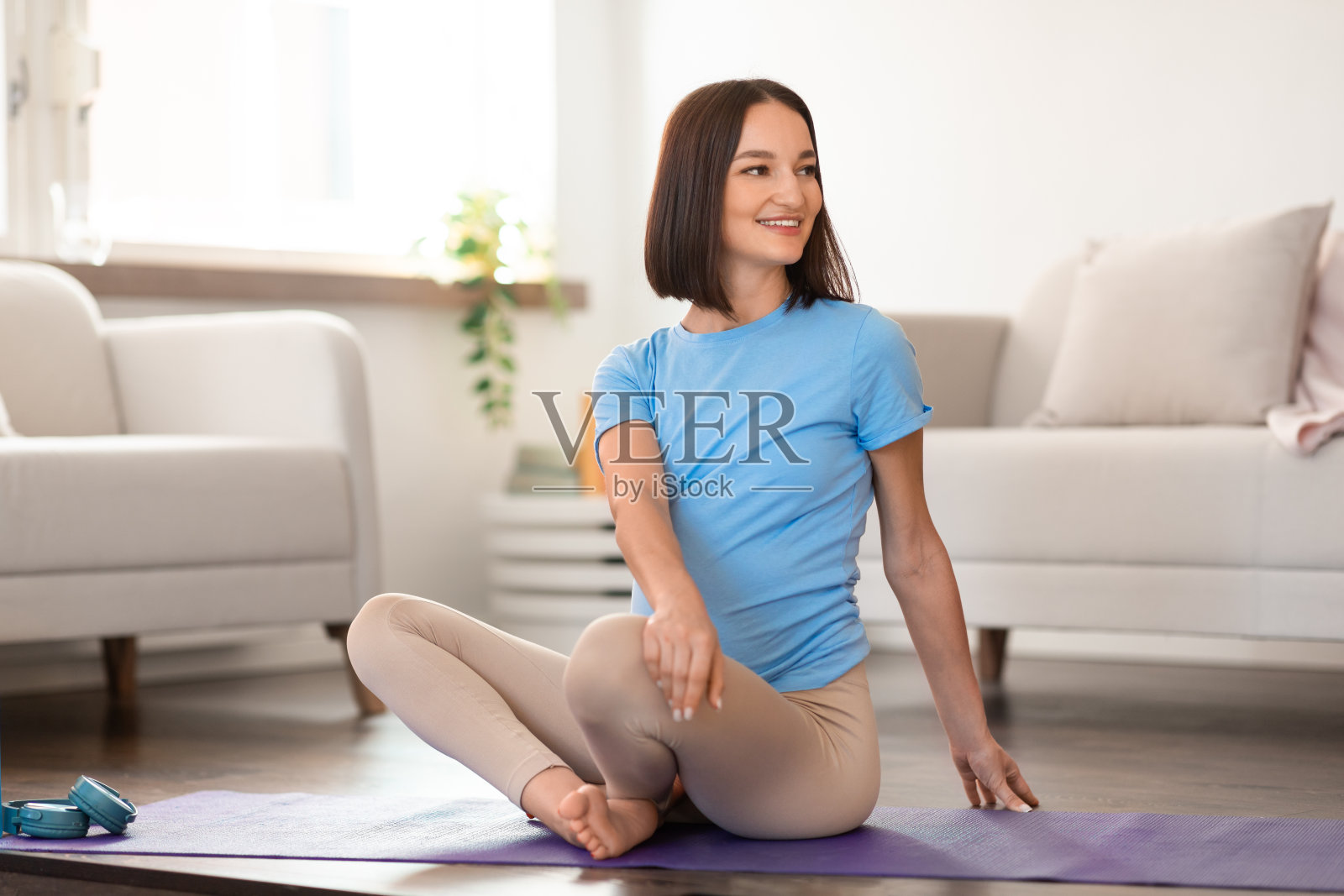 愉快的孕妇在家里做坐姿旋转伸展运动照片摄影图片