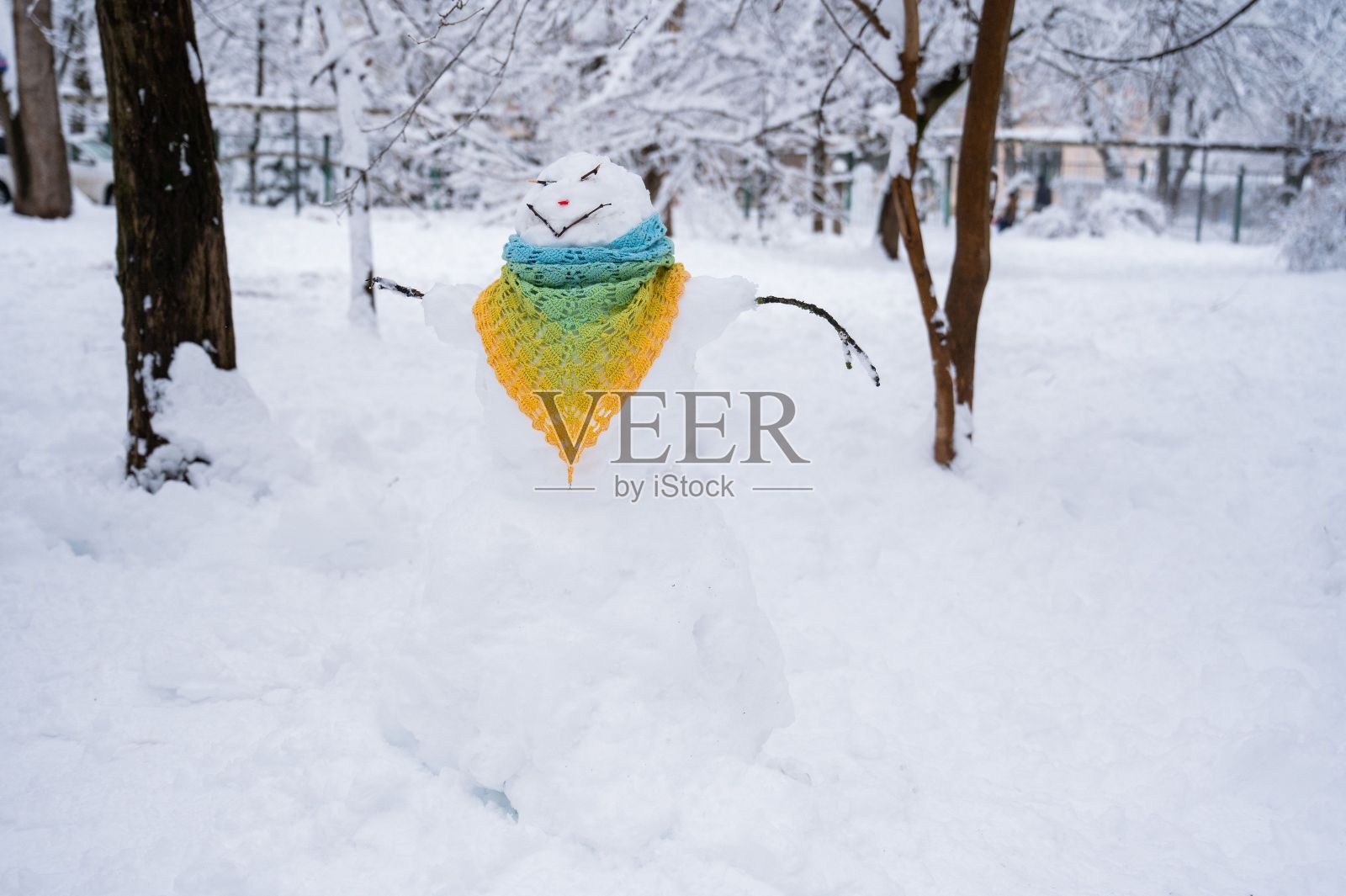 雪人穿着钩针编织的围巾。冬天的乐趣。照片摄影图片