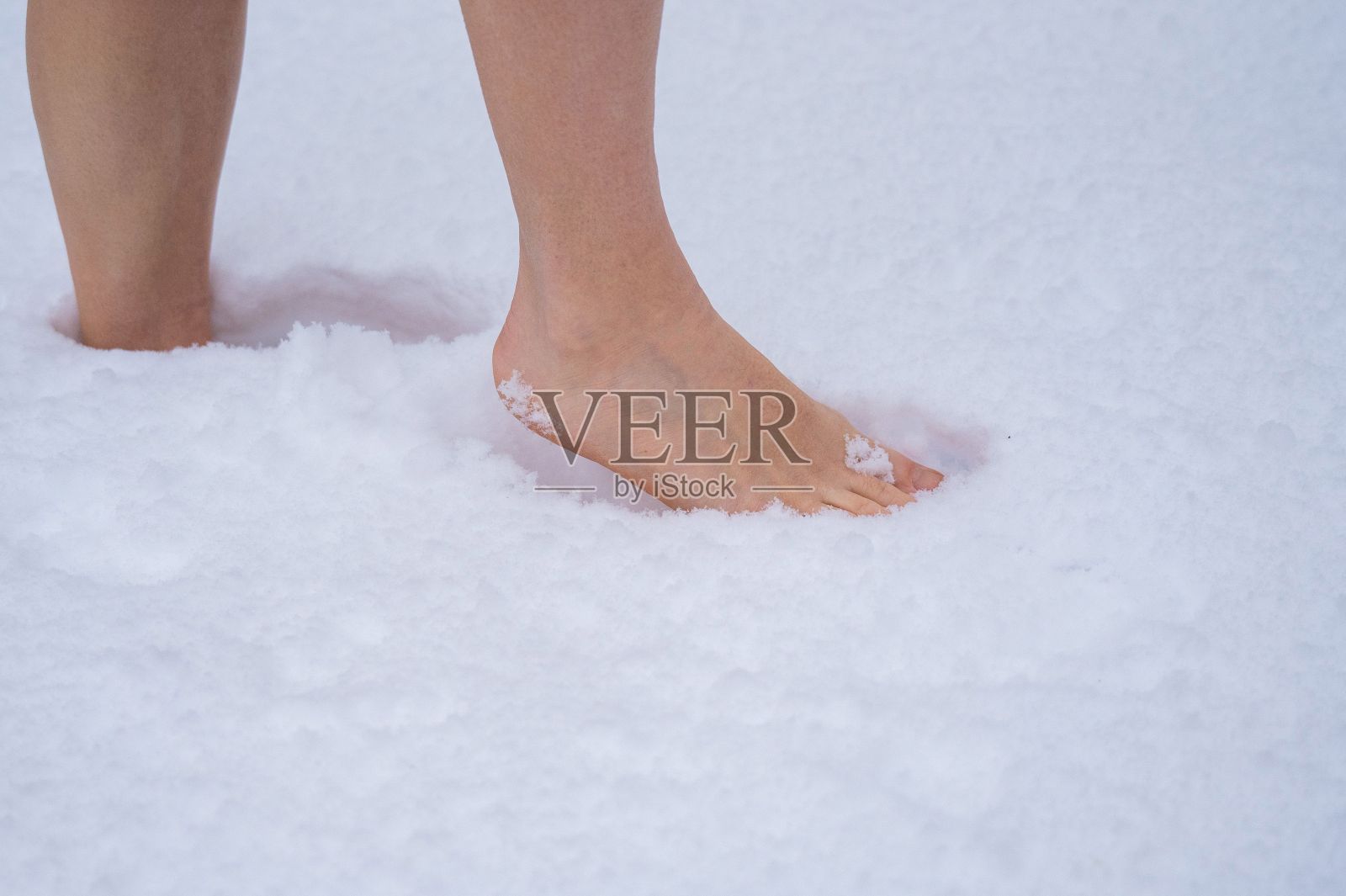 一个女人赤脚走在雪地里的特写。用冷冻疗法增强免疫力。照片摄影图片