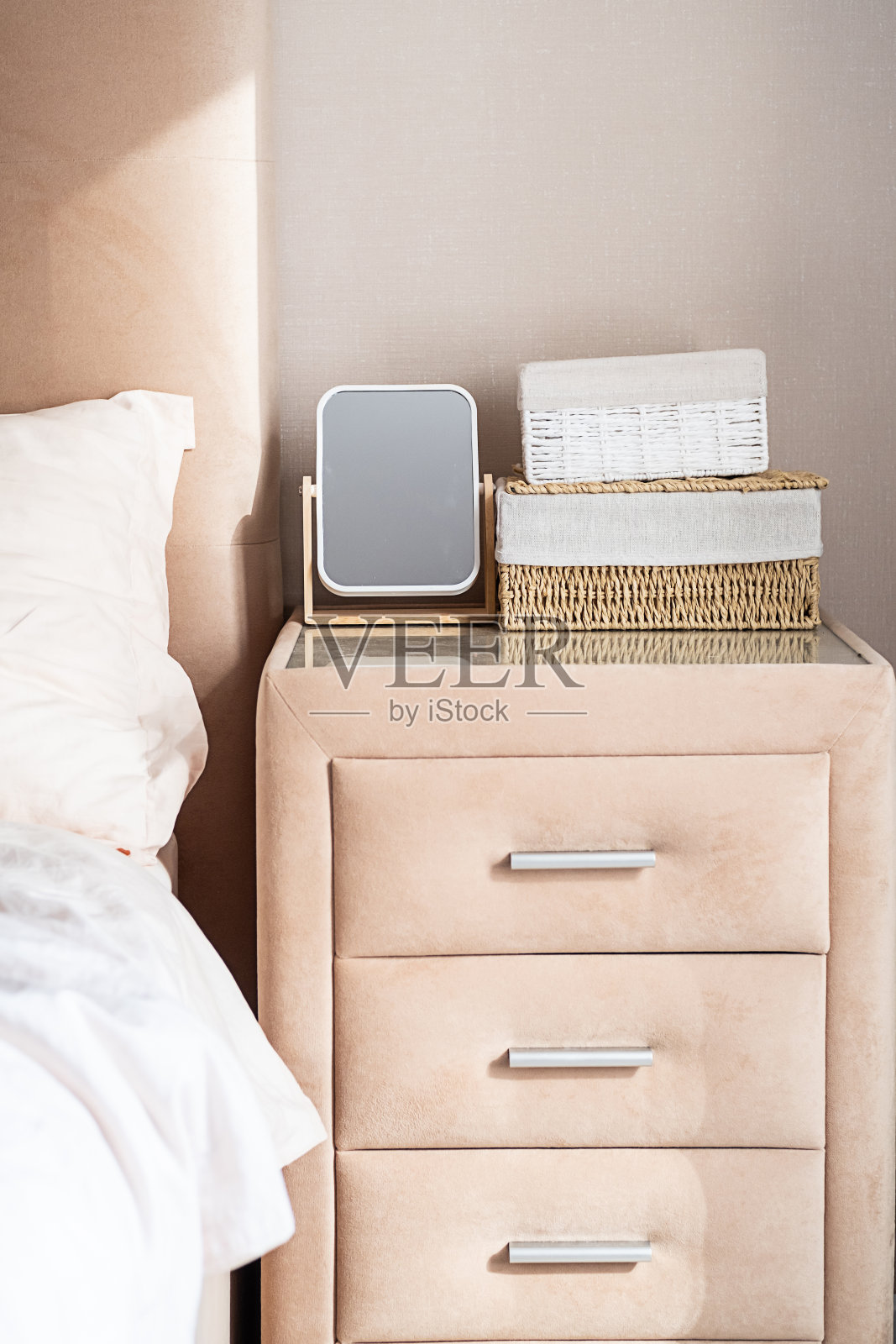 带镜子和储物篮的极简主义卧室床头柜。照片摄影图片