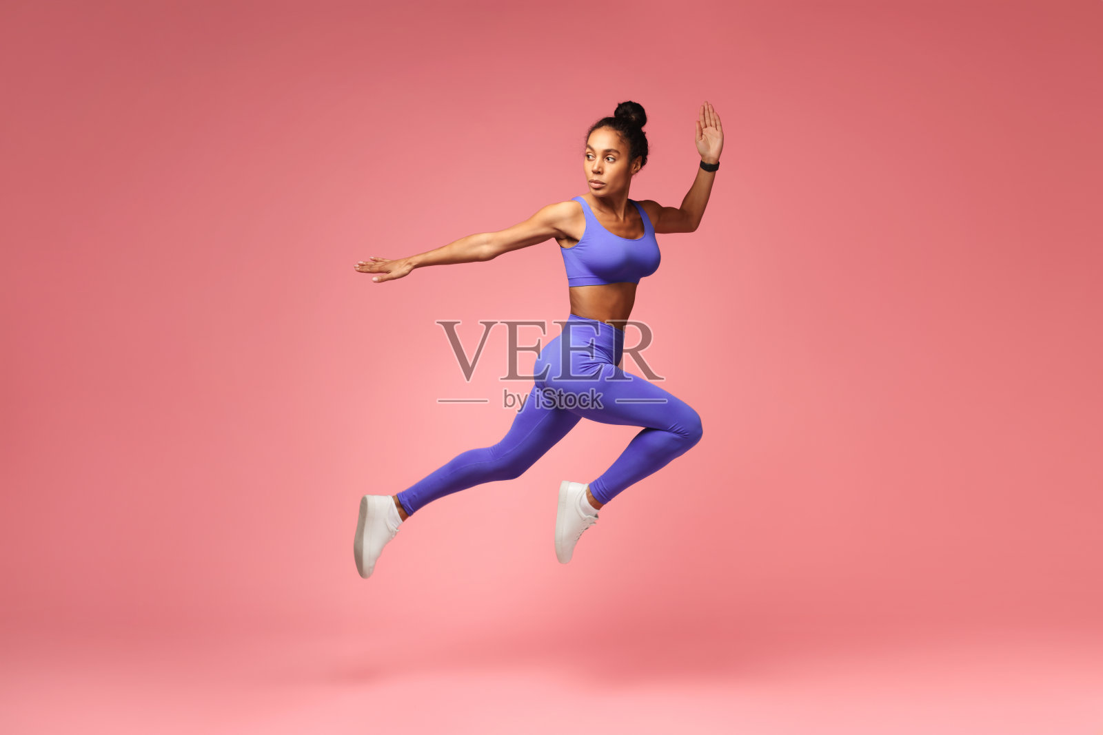 运动员非裔美国人女士跳跃在粉红色的背景下锻炼照片摄影图片