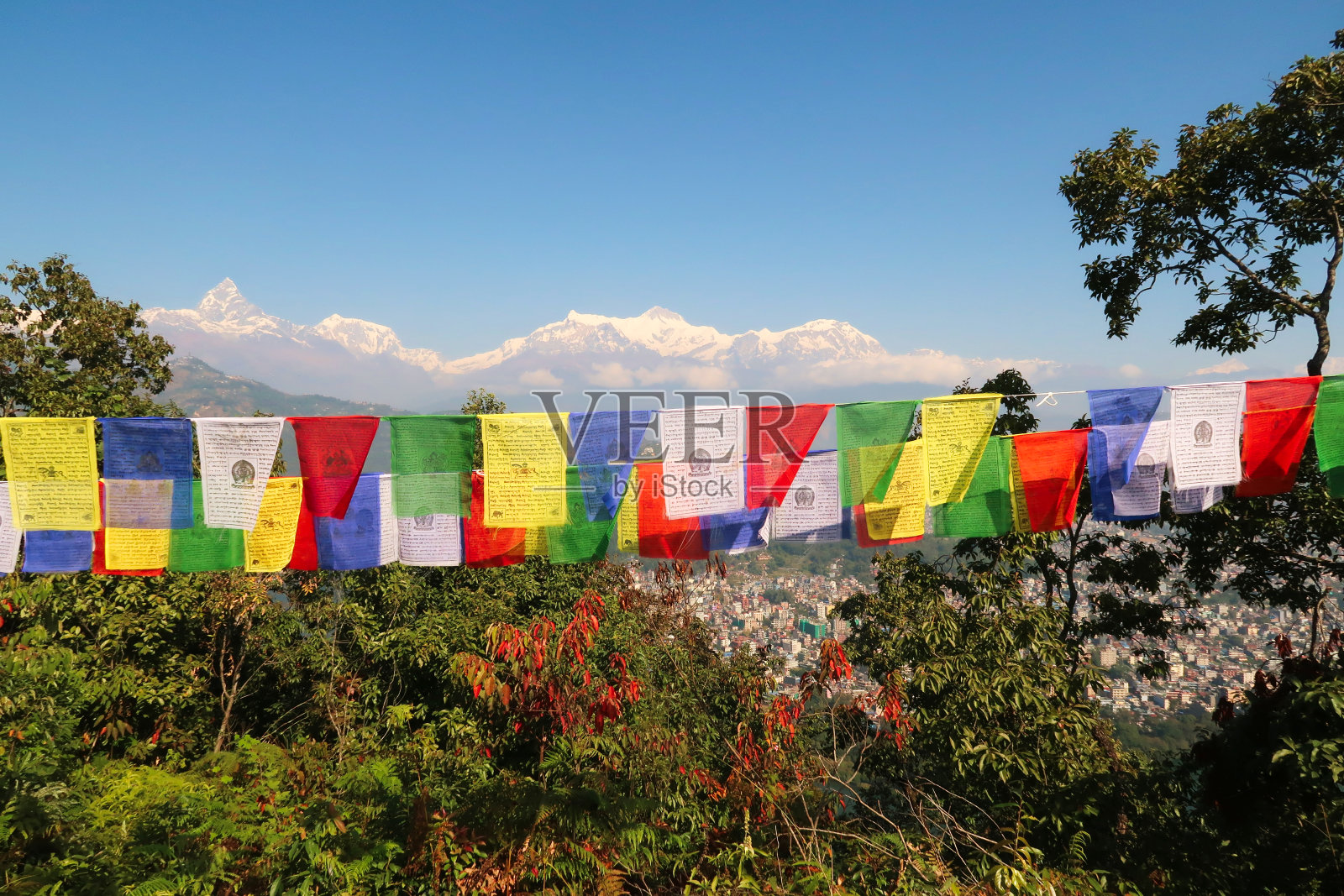 在通往尼泊尔博卡拉的世界和平塔的路上,马沙普查尔在左边,前景是五颜六色的经幡照片摄影图片