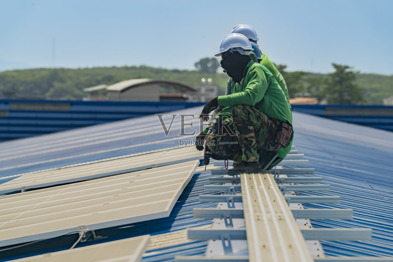 工人技术人员正在屋顶上建造太阳能电池板系统。安装太阳能光伏板系统。男技师走在屋顶结构上检查光伏太阳能组件。照片摄影图片