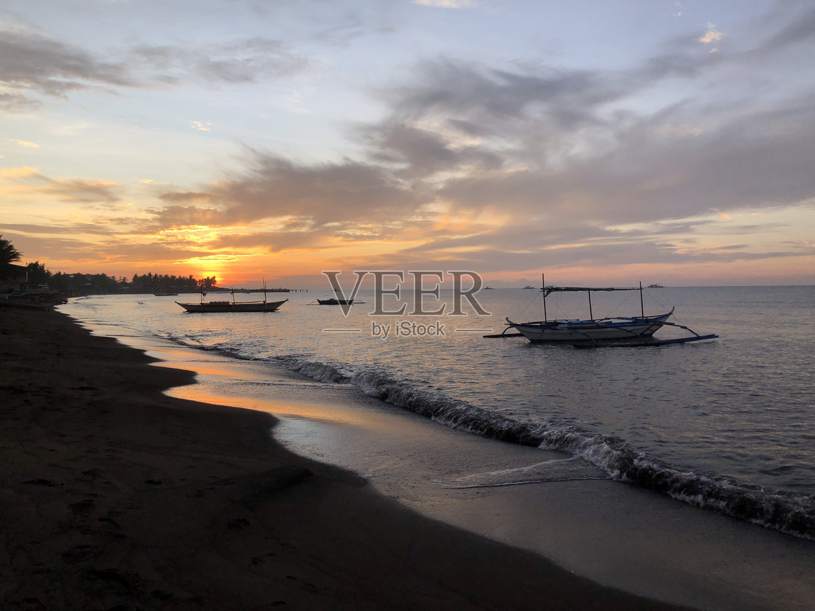 在金色的日出和地平线上的阴天,一艘船停泊在海边的美丽景色。轮廓照片摄影图片