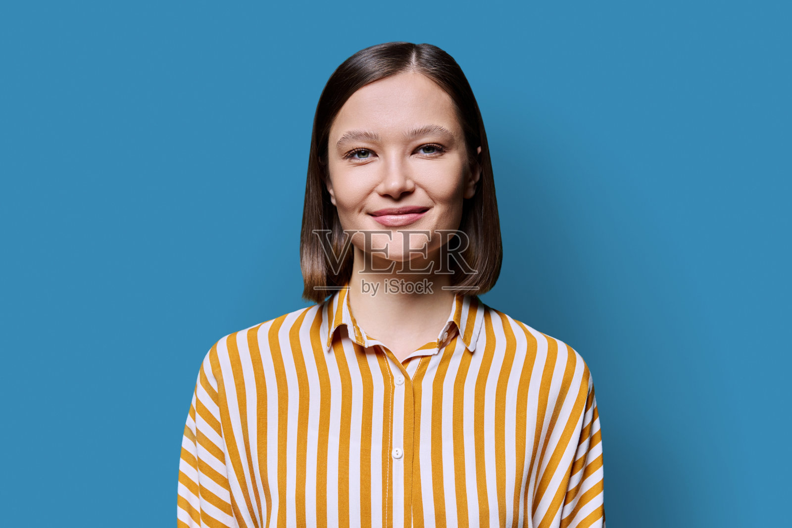 年轻的微笑迷人的女人在蓝色的背景照片摄影图片