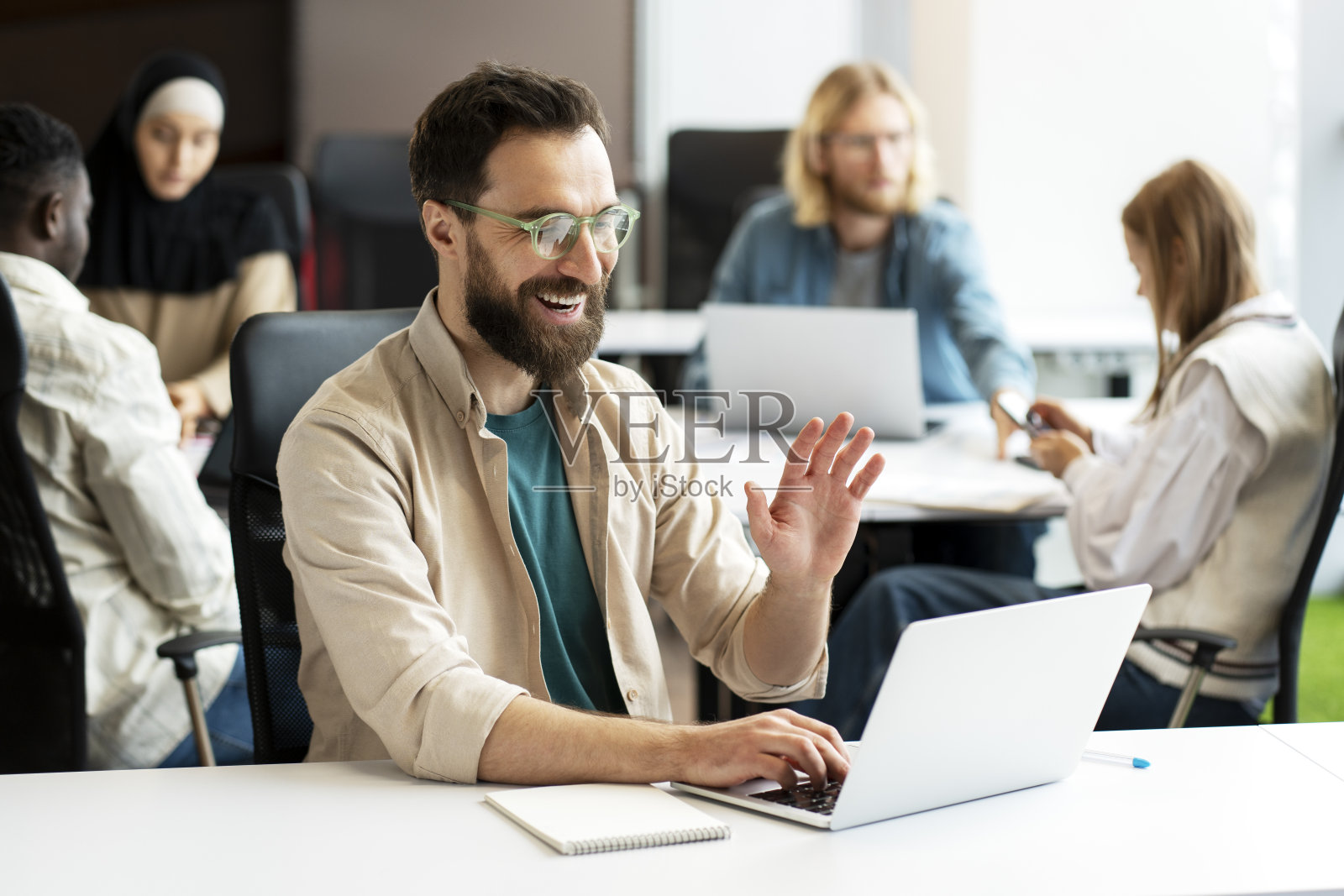 快乐的商人,迷人的潮人在繁忙的办公室视频通话中招手照片摄影图片