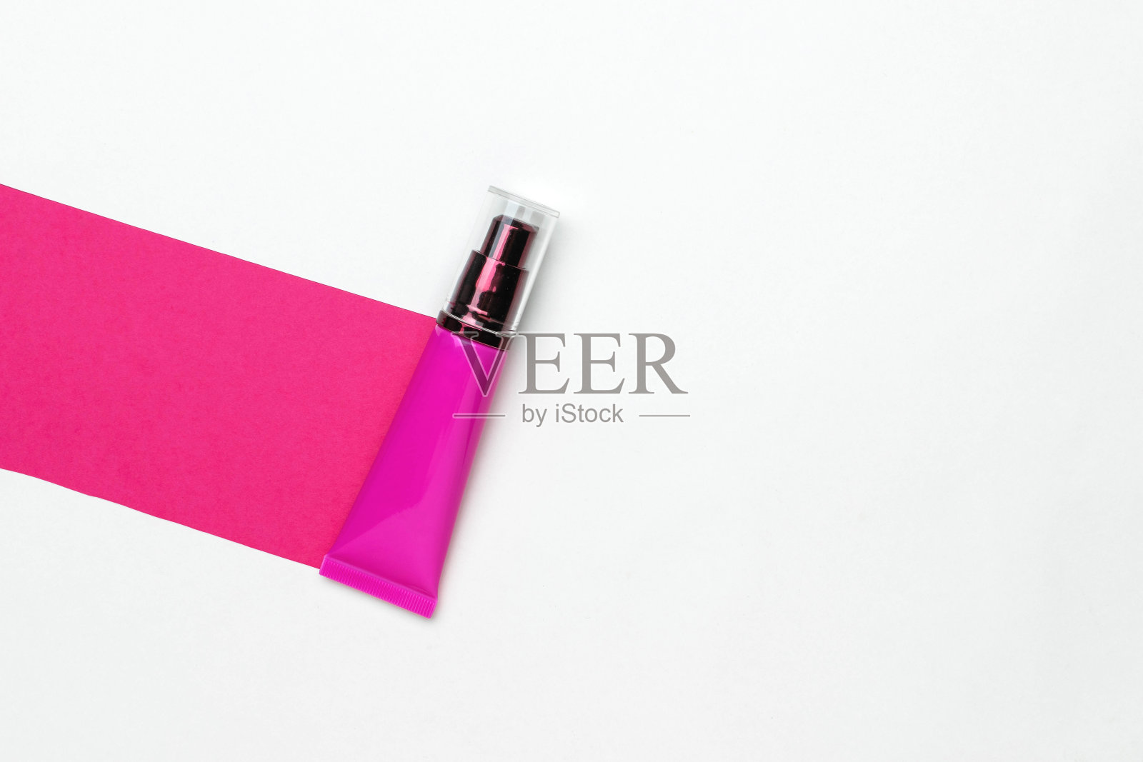 粉红色乳液管上充满活力的粉红色条与极简主义的白色背景-现代护肤概念照片摄影图片