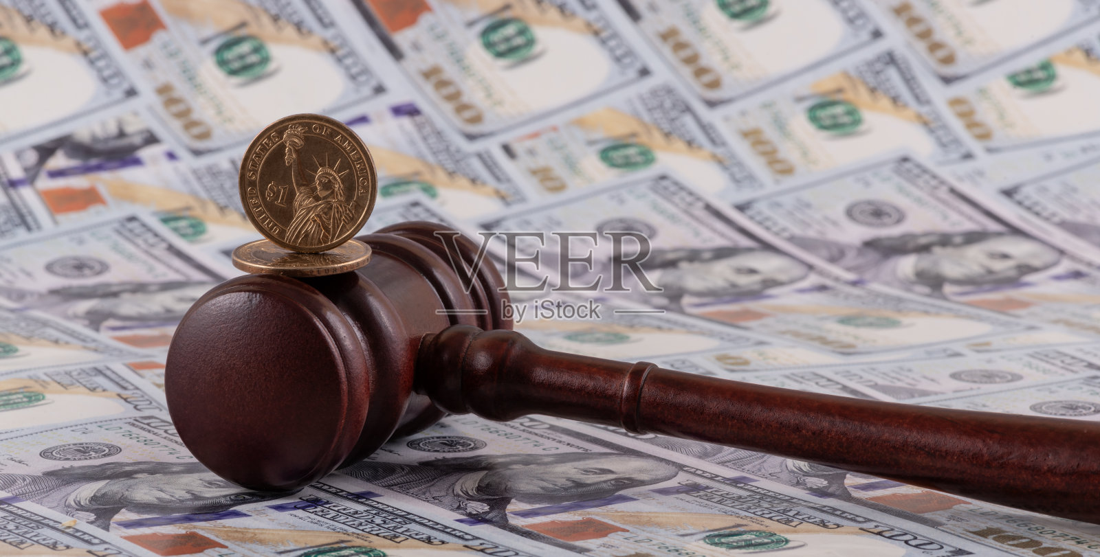 1美元硬币和法官的木槌,背景是100美元钞票照片摄影图片