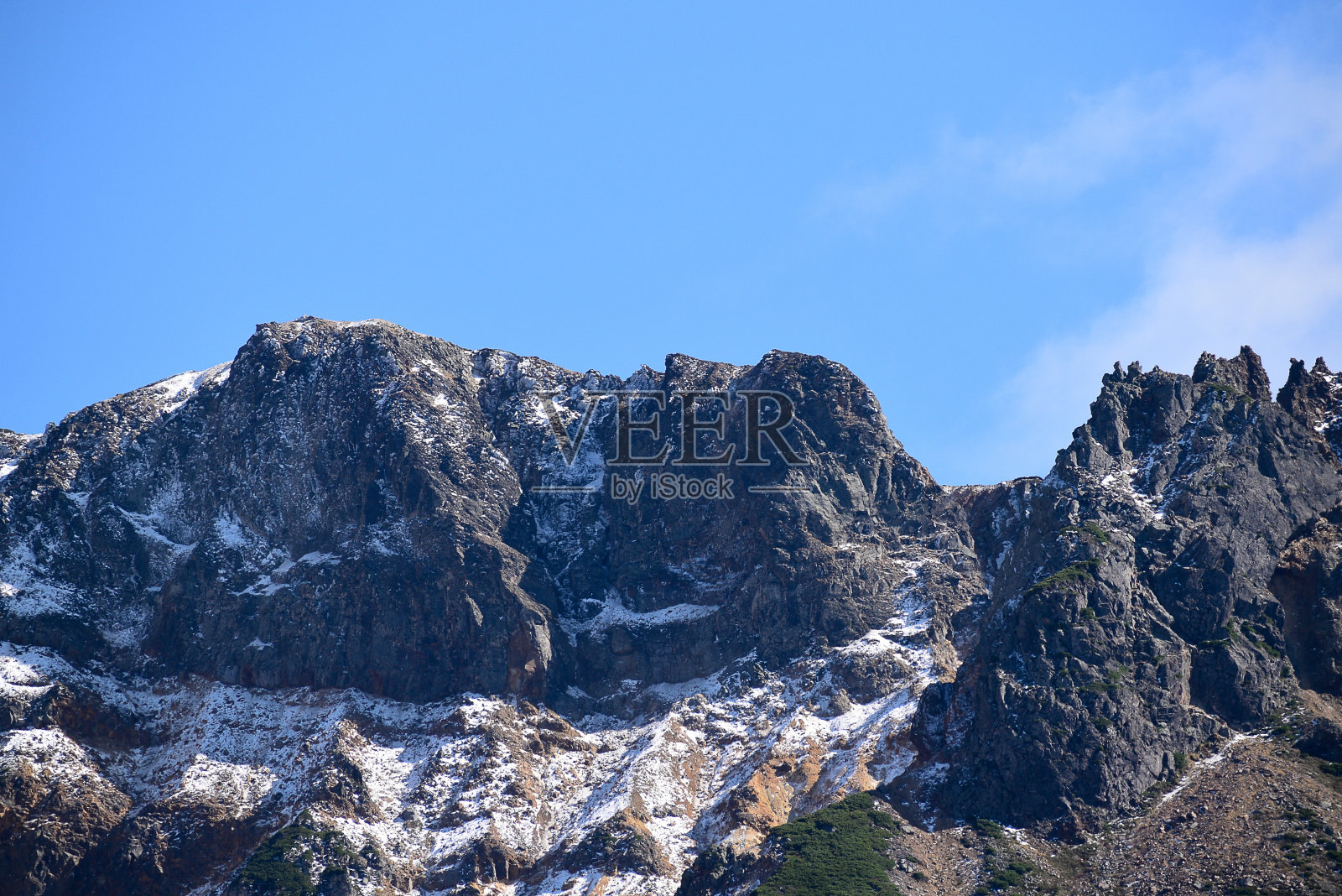 秋天被雪覆盖的岩石山峰,背景是蓝天照片摄影图片