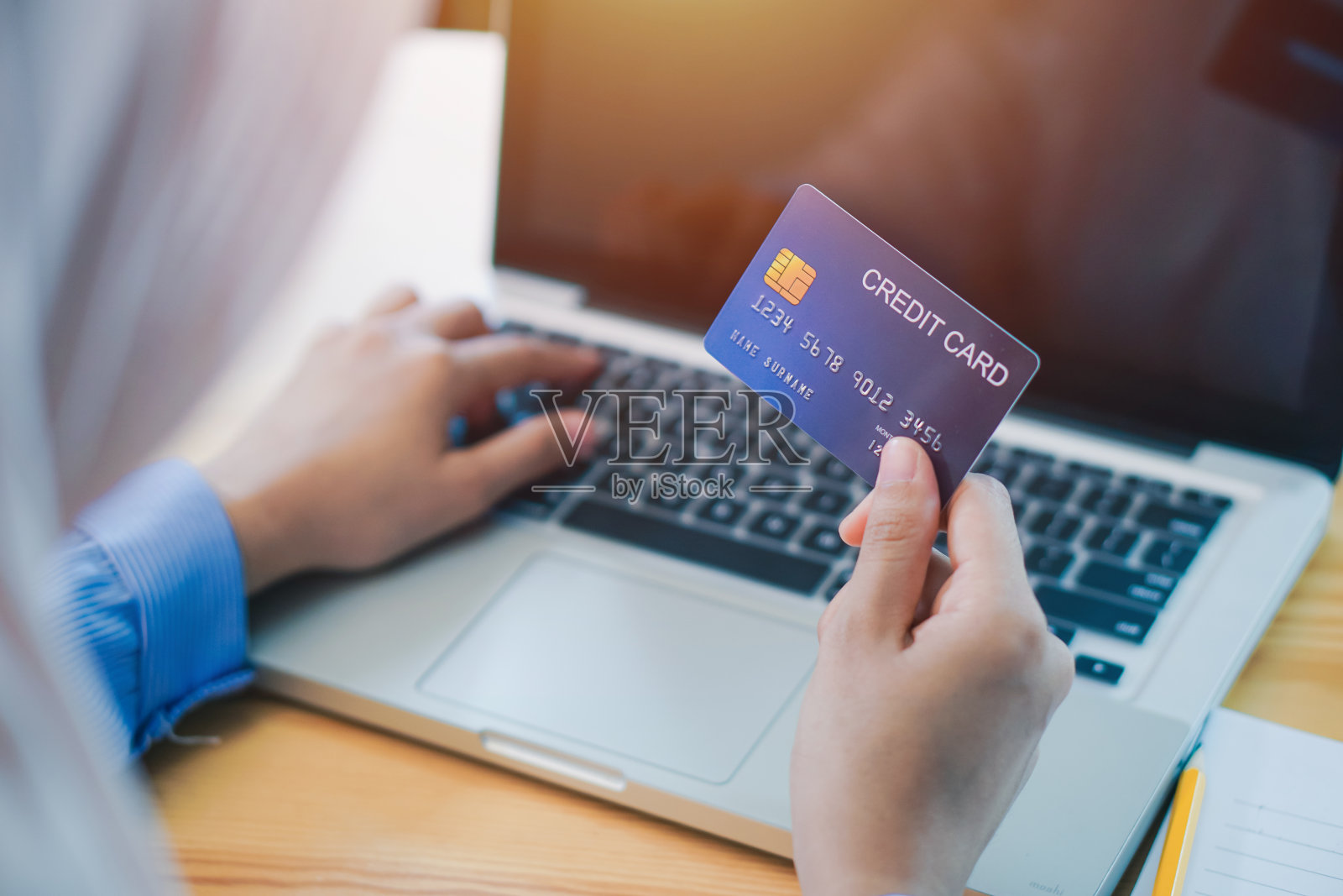 女商人在办公室使用笔记本电脑时拿着信用卡的裁剪手照片摄影图片