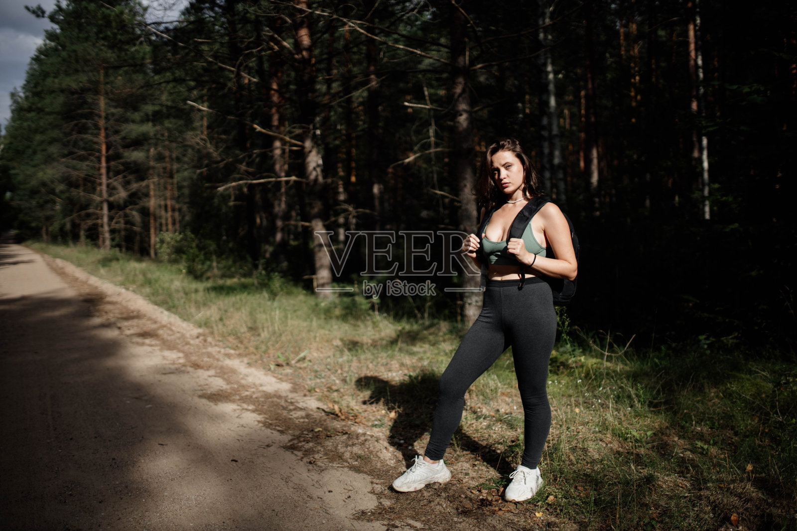 穿着运动服背着背包在森林里的女人照片摄影图片