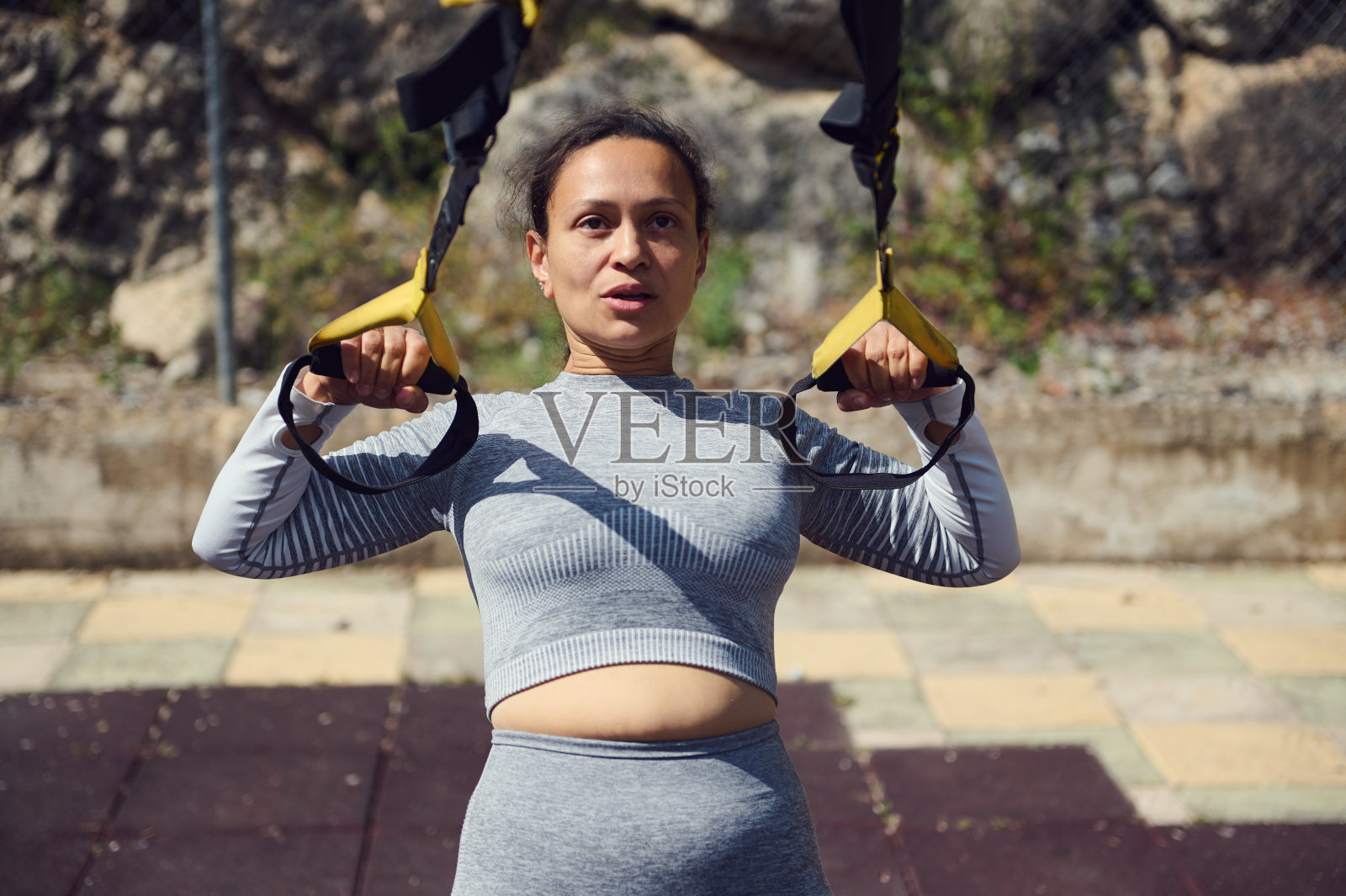 女人在户外用TRX悬挂训练器进行健身和力量训练照片摄影图片