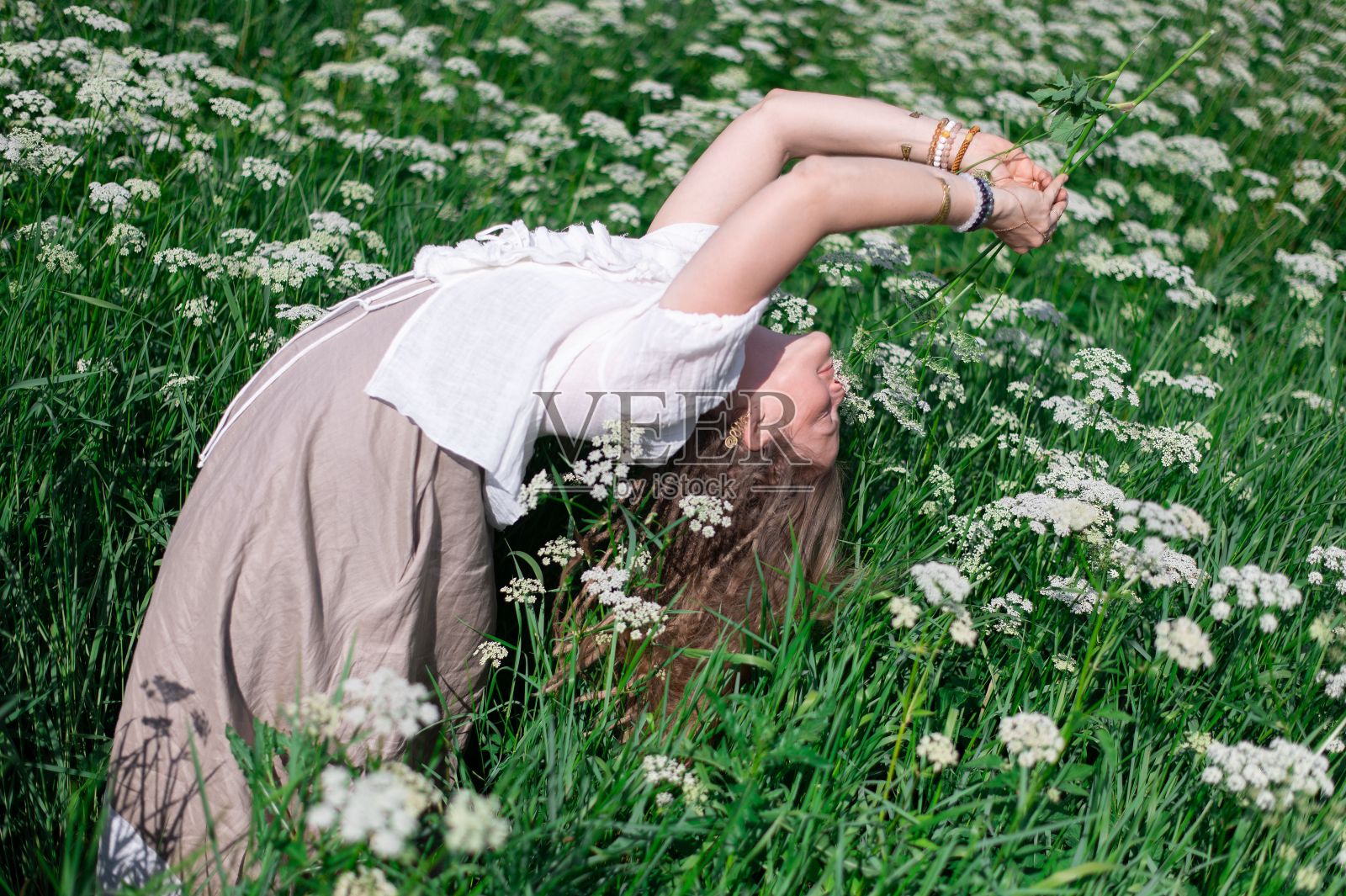 在一个阳光明媚的日子里,年轻女子在白色的野花地里摆姿势照片摄影图片
