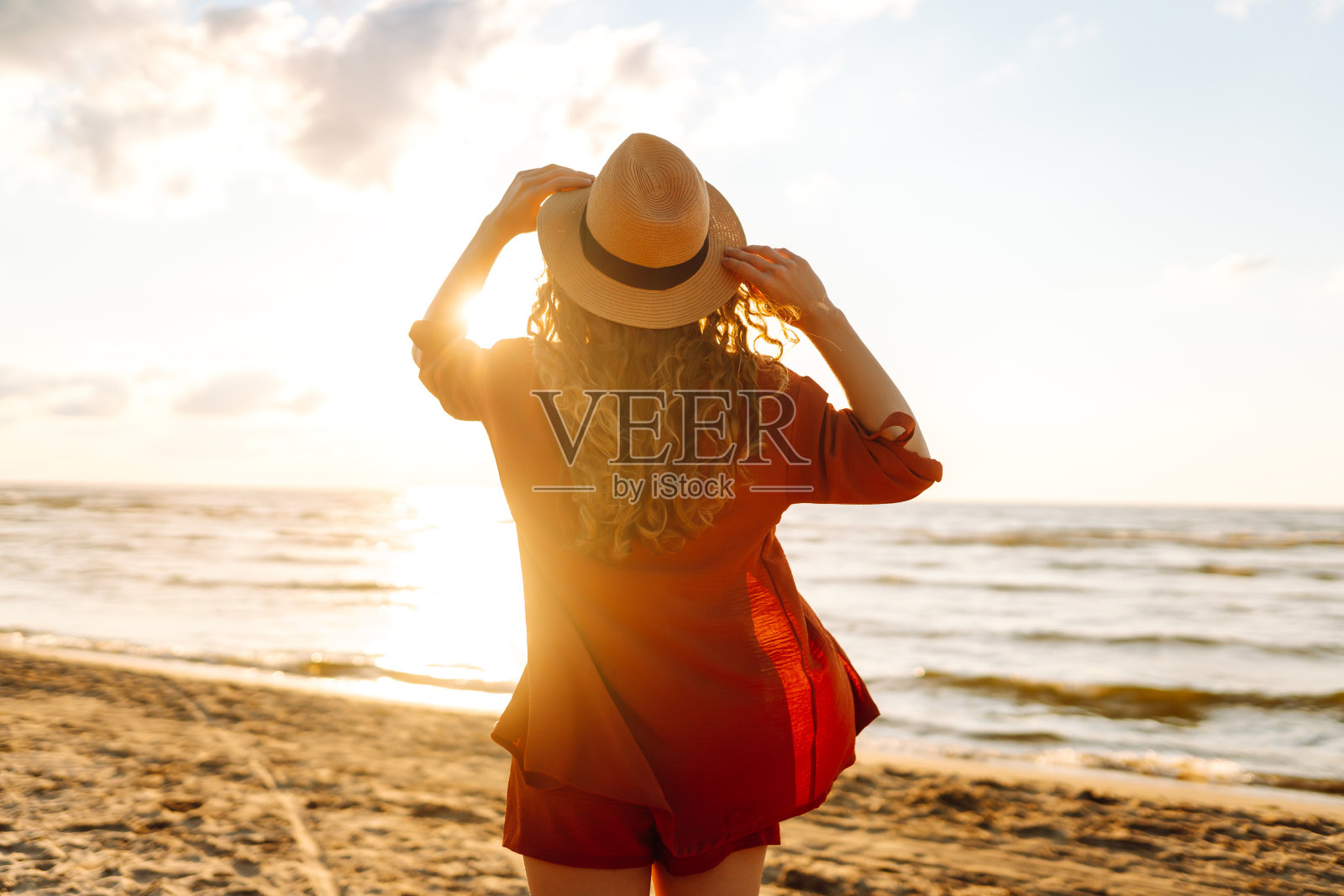 美丽的女人在日落的海滩上享受夏日。照片摄影图片