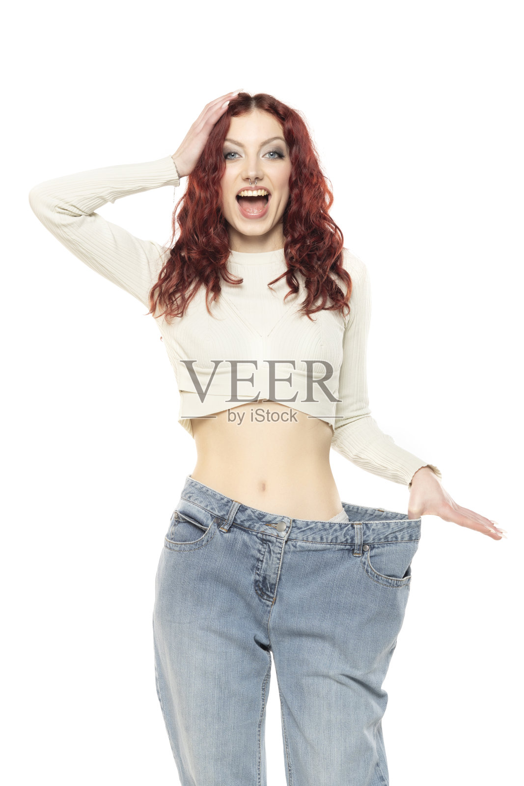 年轻快乐的红发女人在展示她减了多少体重。健康生活方式的概念。白色背景。照片摄影图片