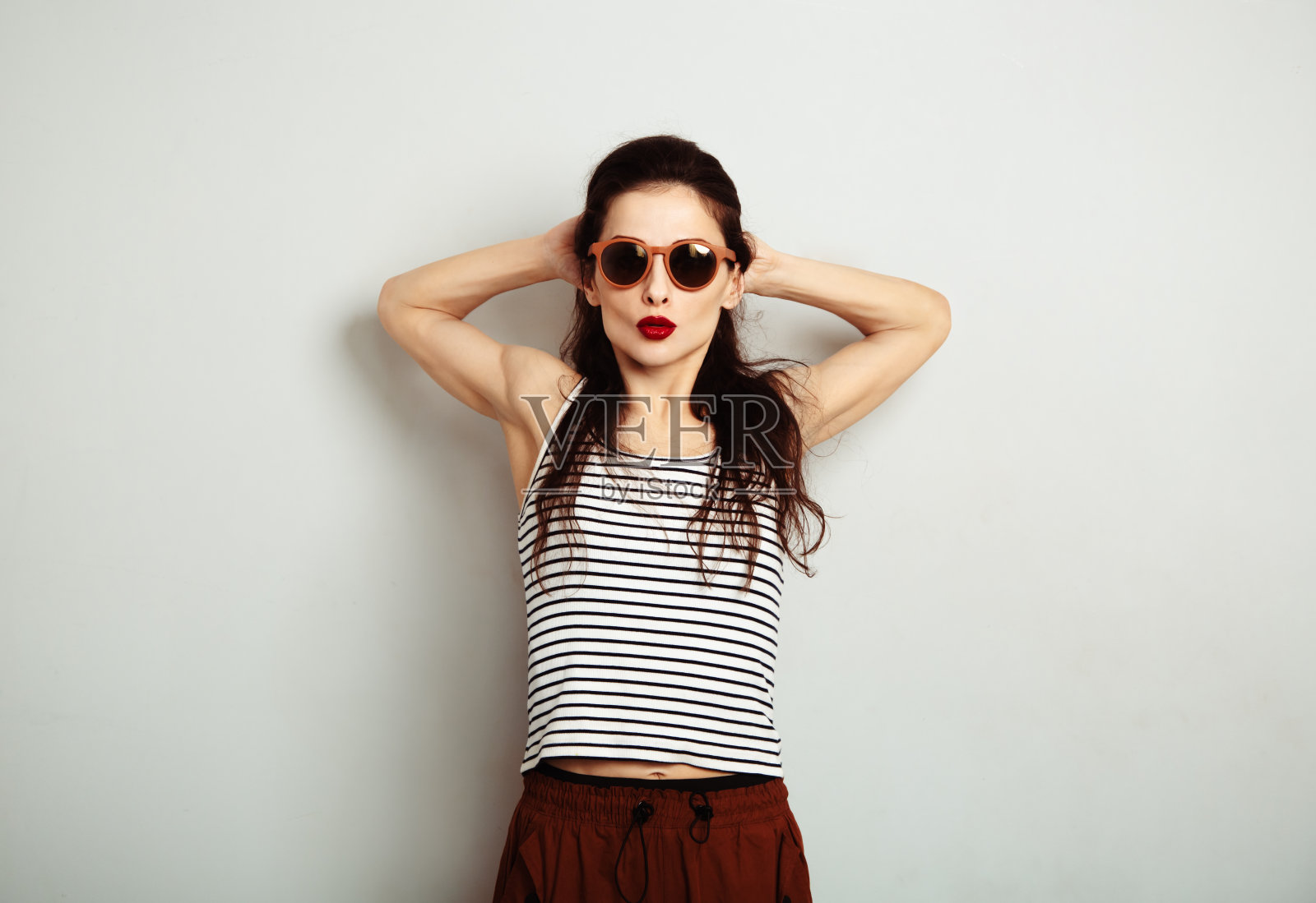 有趣放松微笑的女人摆出时尚的太阳镜和剥离的t恤,红色的口红在白色的墙壁背景与空白的复制空间。快乐时尚生活方式照片摄影图片
